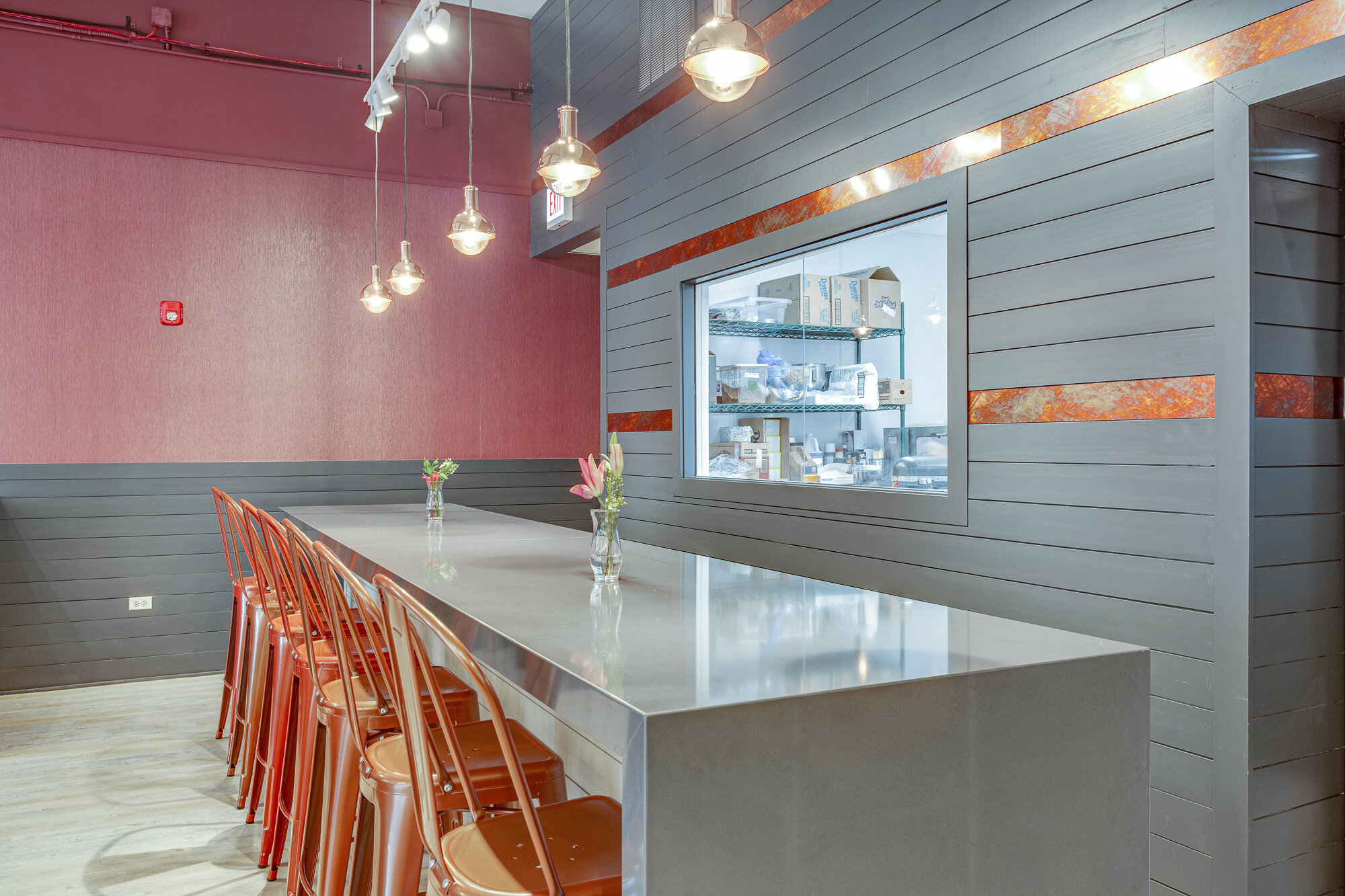 Inviting restaurant seating with cooper stools, Mitzi pendent lights and an accent wall in shiplap with copper painted in Benjamin Moore Wrought Iron (2124-10) in La Grange.