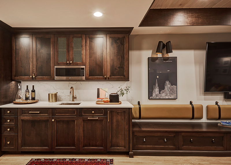 A basement kitchenette, perfect for hosting complete with custom shaker cabinets, quartz counters, and brass hardware. Design by Two Hands Interiors.