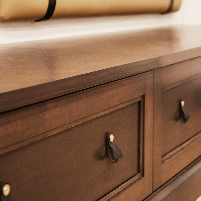 Custom leather pulls from Walnut Studio add charm to basement storage and additional seating. Design by Two Hands Interiors.