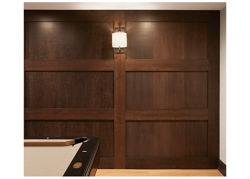 A basement feature wall with stained custom panels and wall sconces set off a pool table behind a Crate and Barrel Petite Lounge sectional. LVP floor (luxury vinyl plank) provides extra durability.