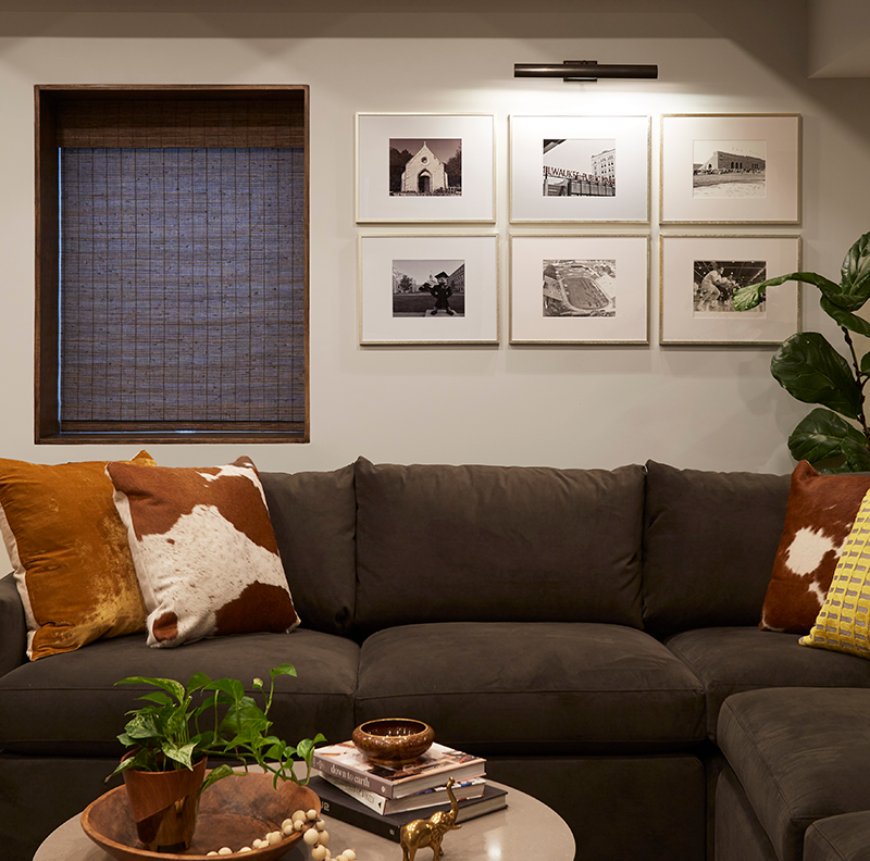 A gallery wall of vintage black and white photography from the family’s alma maters brings a personal touch to this inviting basement. Frames from Target, RH picture light sconce. 