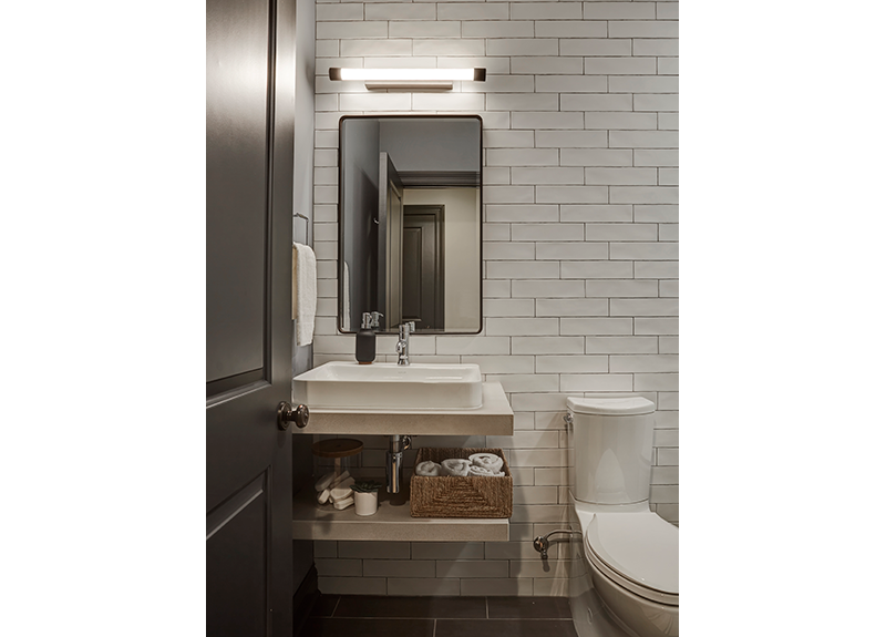 Subway tile, custom open sink made of slab porcelain and a Pottery Barn low profile mirror keep this basement bathroom modern and functional. Design by Two Hands Interiors.
