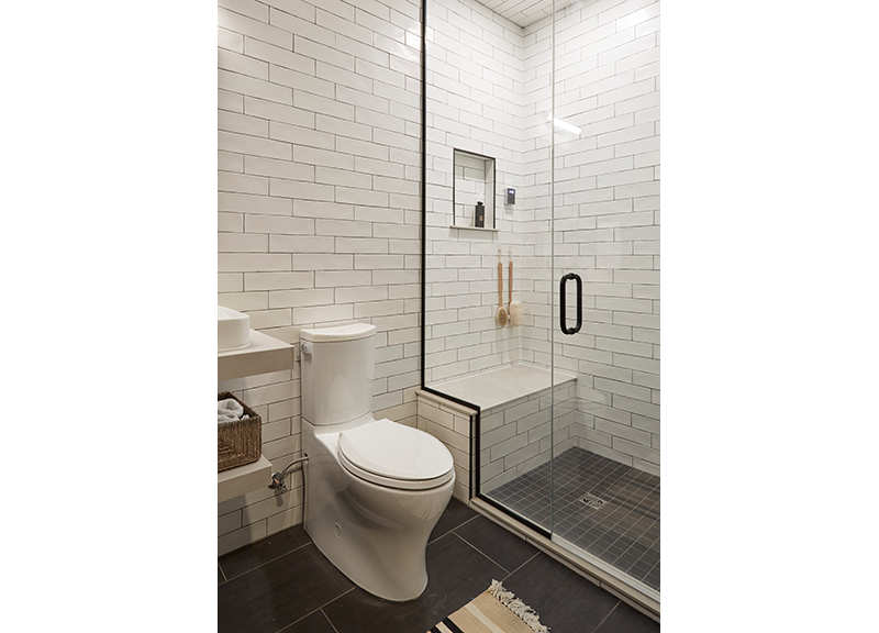 Subway tile clad basement bathroom offers a simple and clean steam shower. Design by Two Hands Interiors.