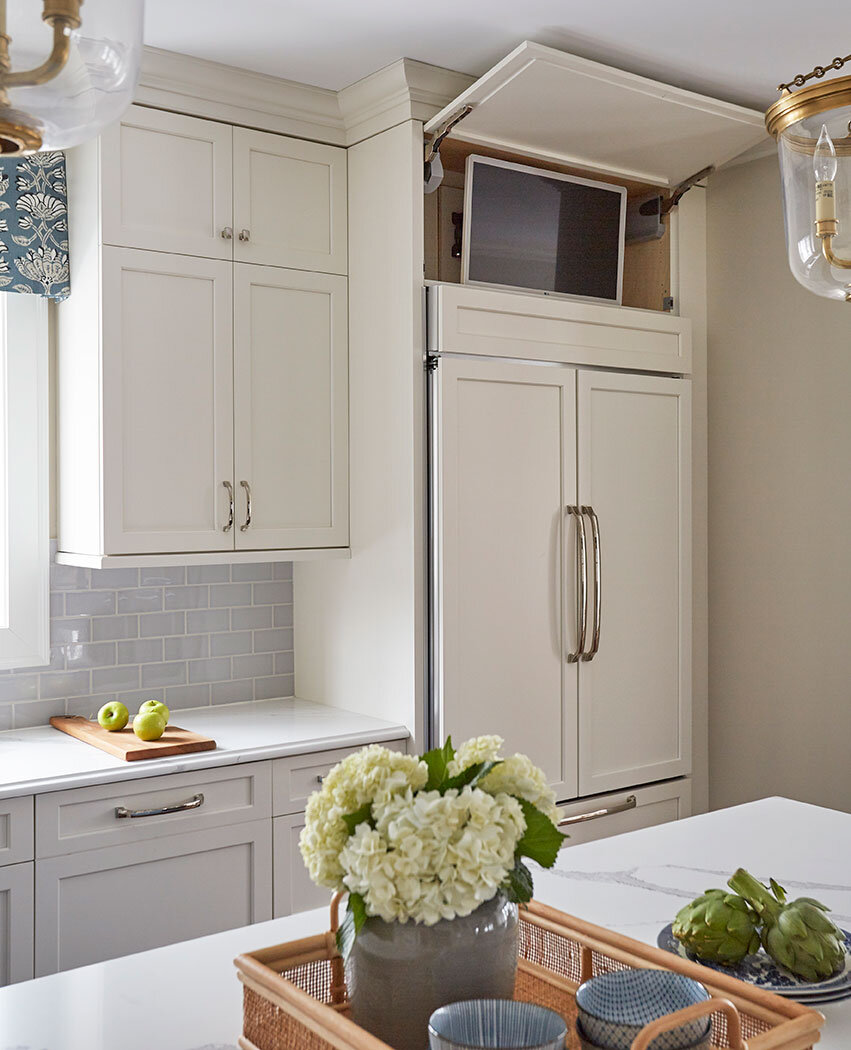 White shaker cabinets in kitchen reveal television