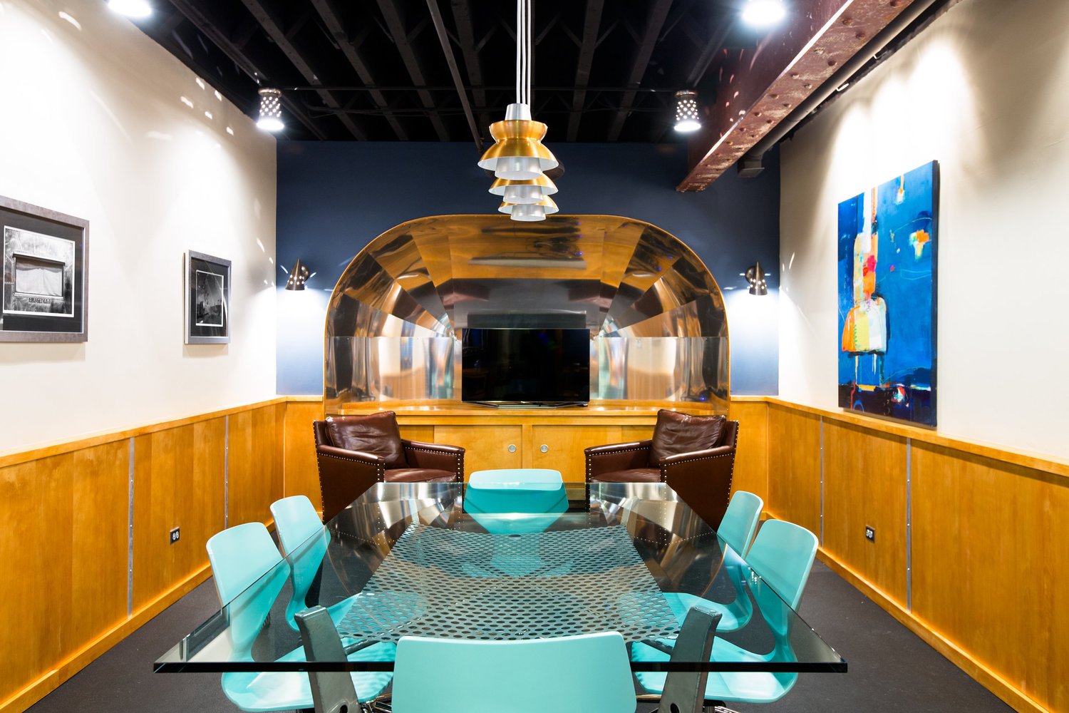 Authentic shellacked plywood and airplane grade aluminum were used to set the stage in this airstream inspired conference room. Design by Two Hands Interiors. 