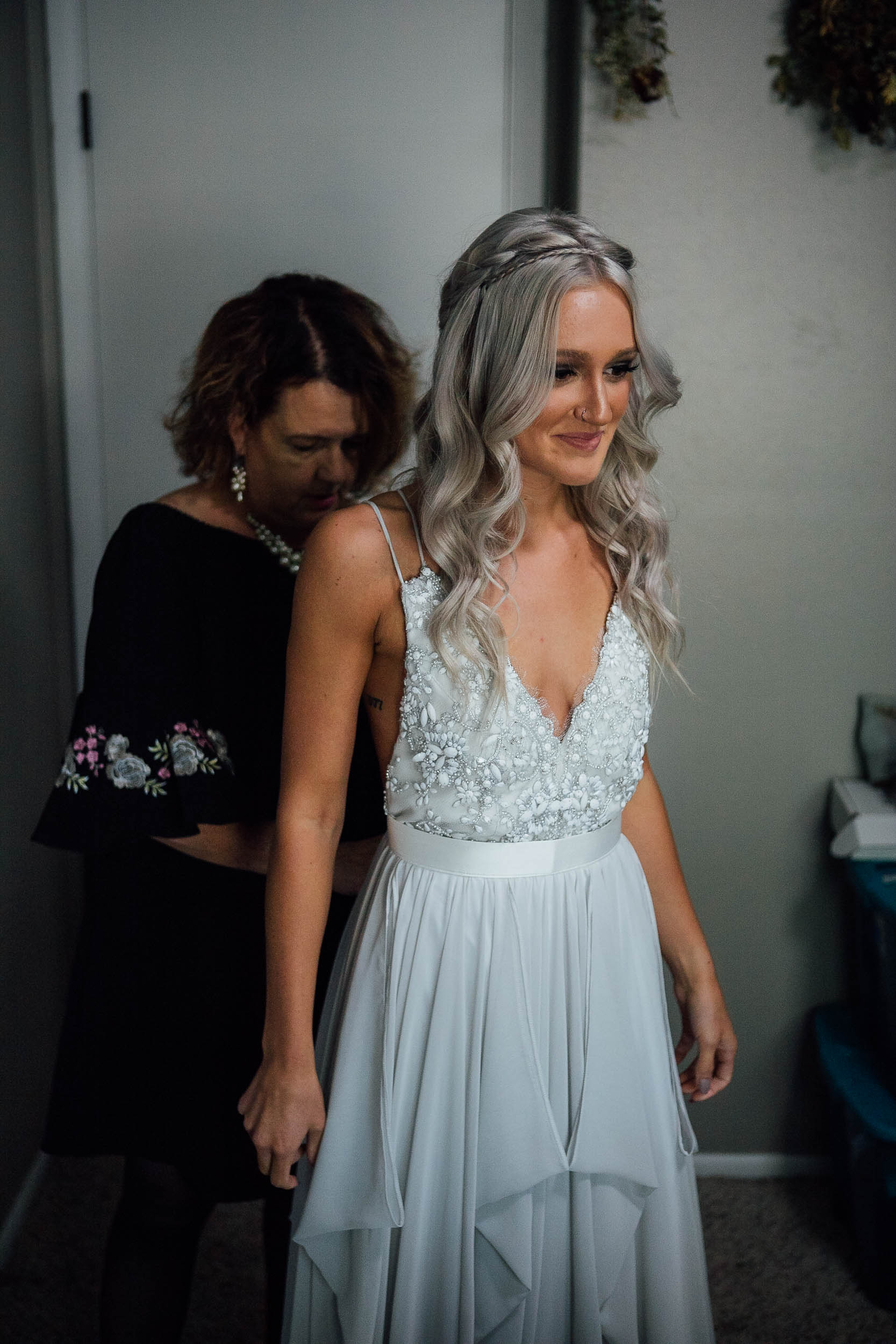 Mother of the bride helping bride put on her wedding dress