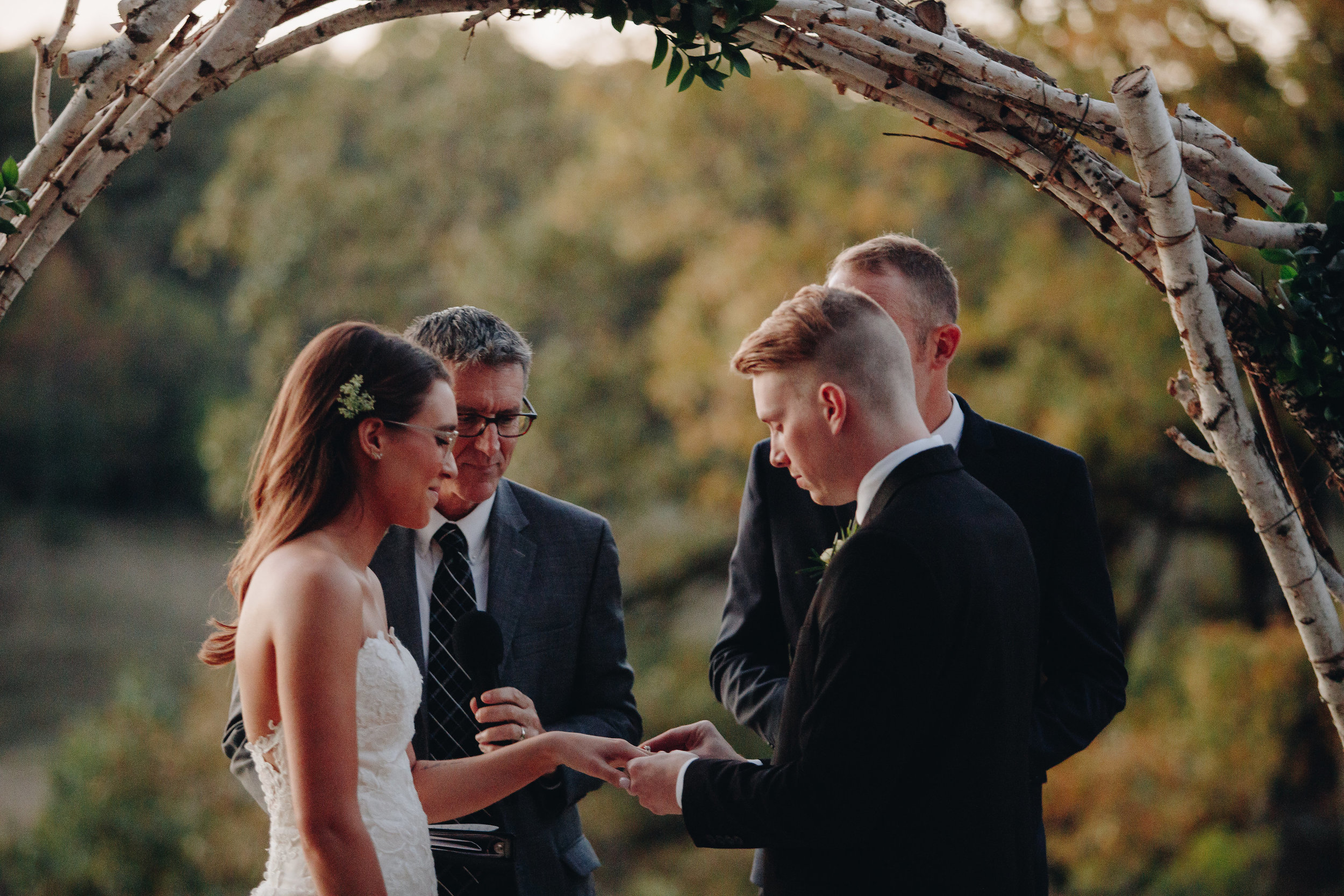 Groom putting ring bride outdoor Minnesota wedding photographers