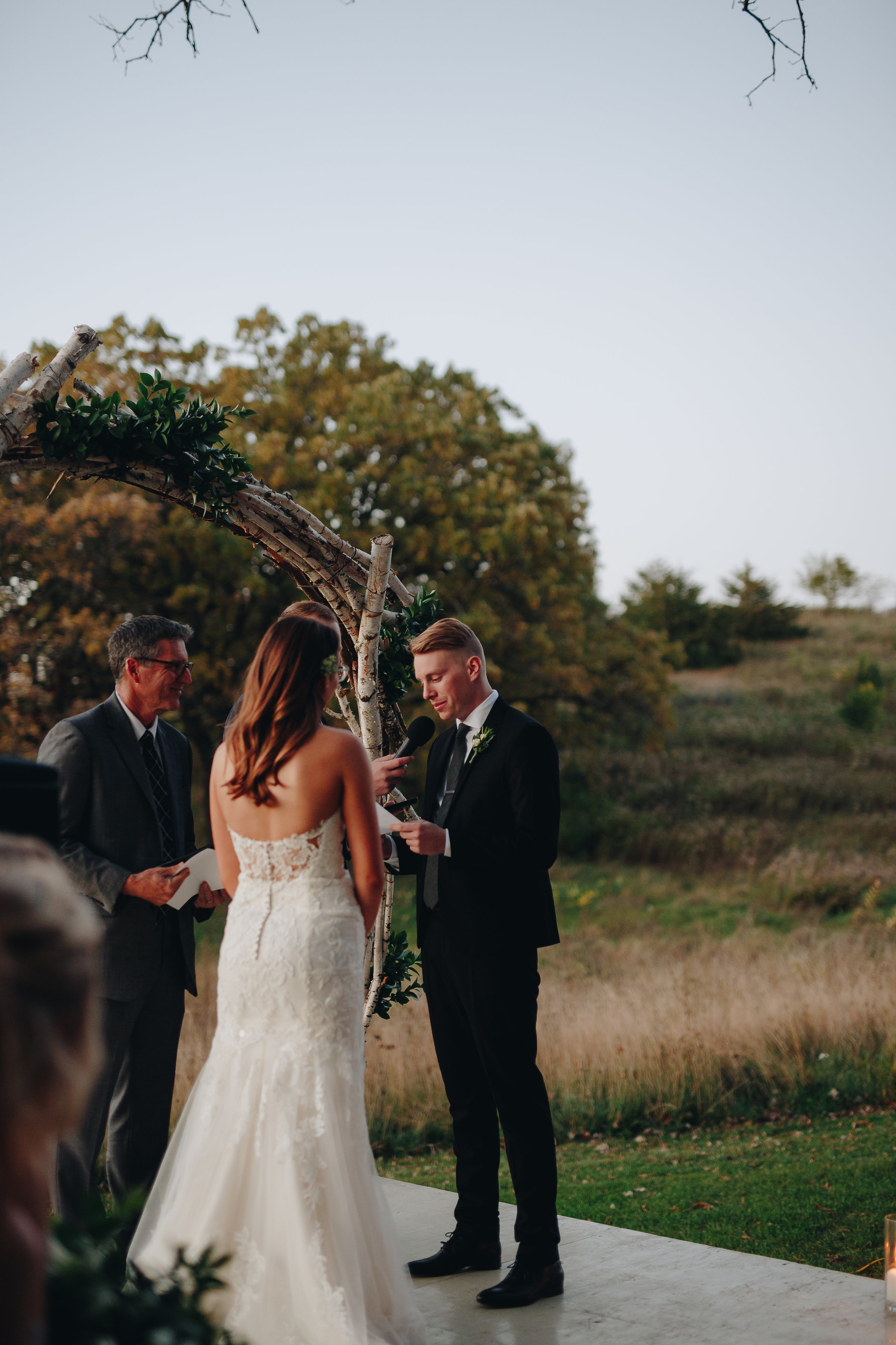 Groom reading vows to his bride at dusk wedding ceremony in Minnesota