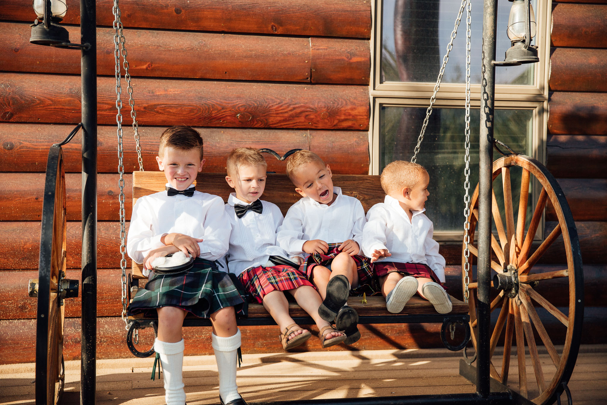 Four little boys in kilts sitting on a swing