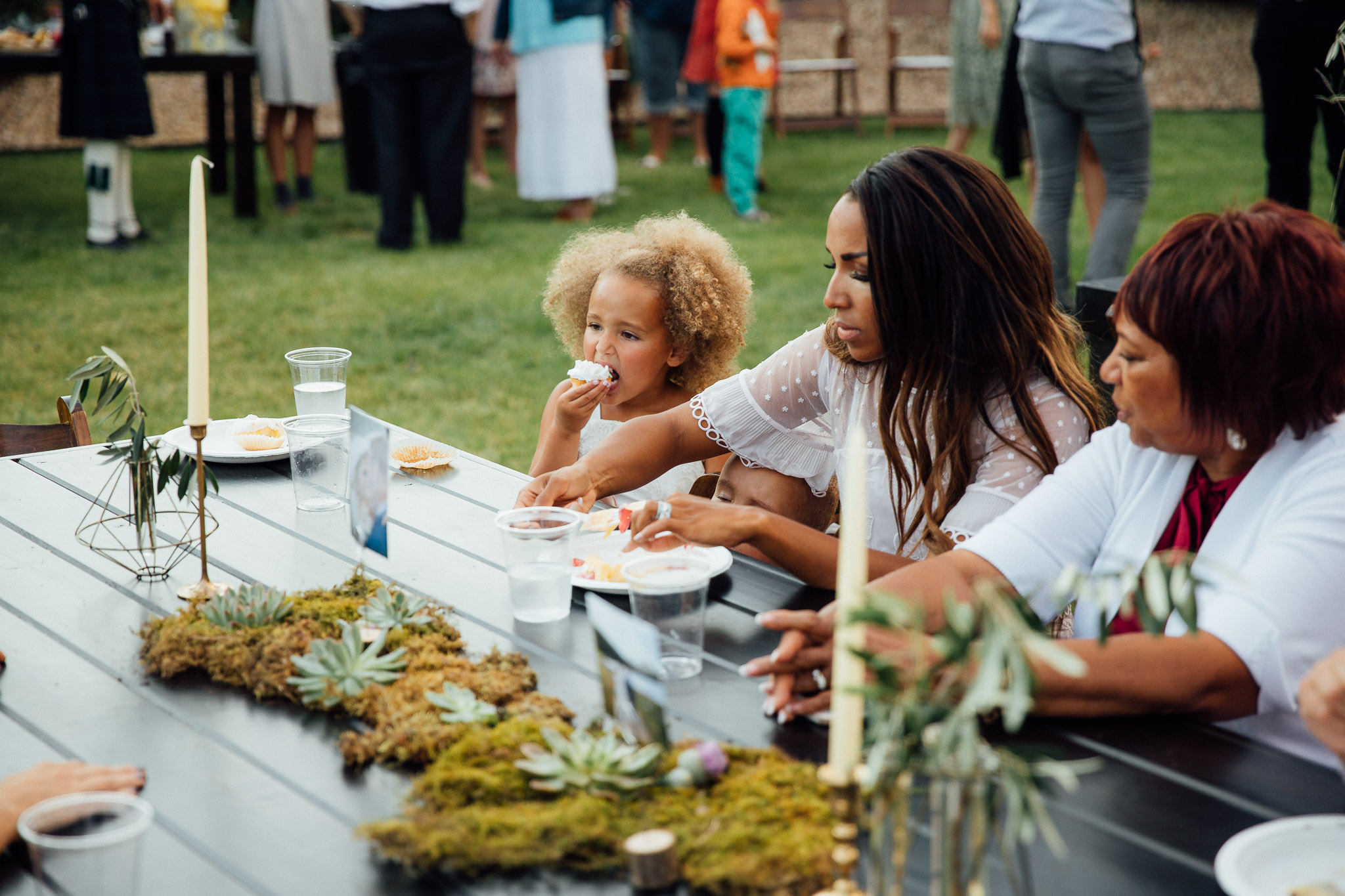 Flower girl eats cupcake at wedding reception