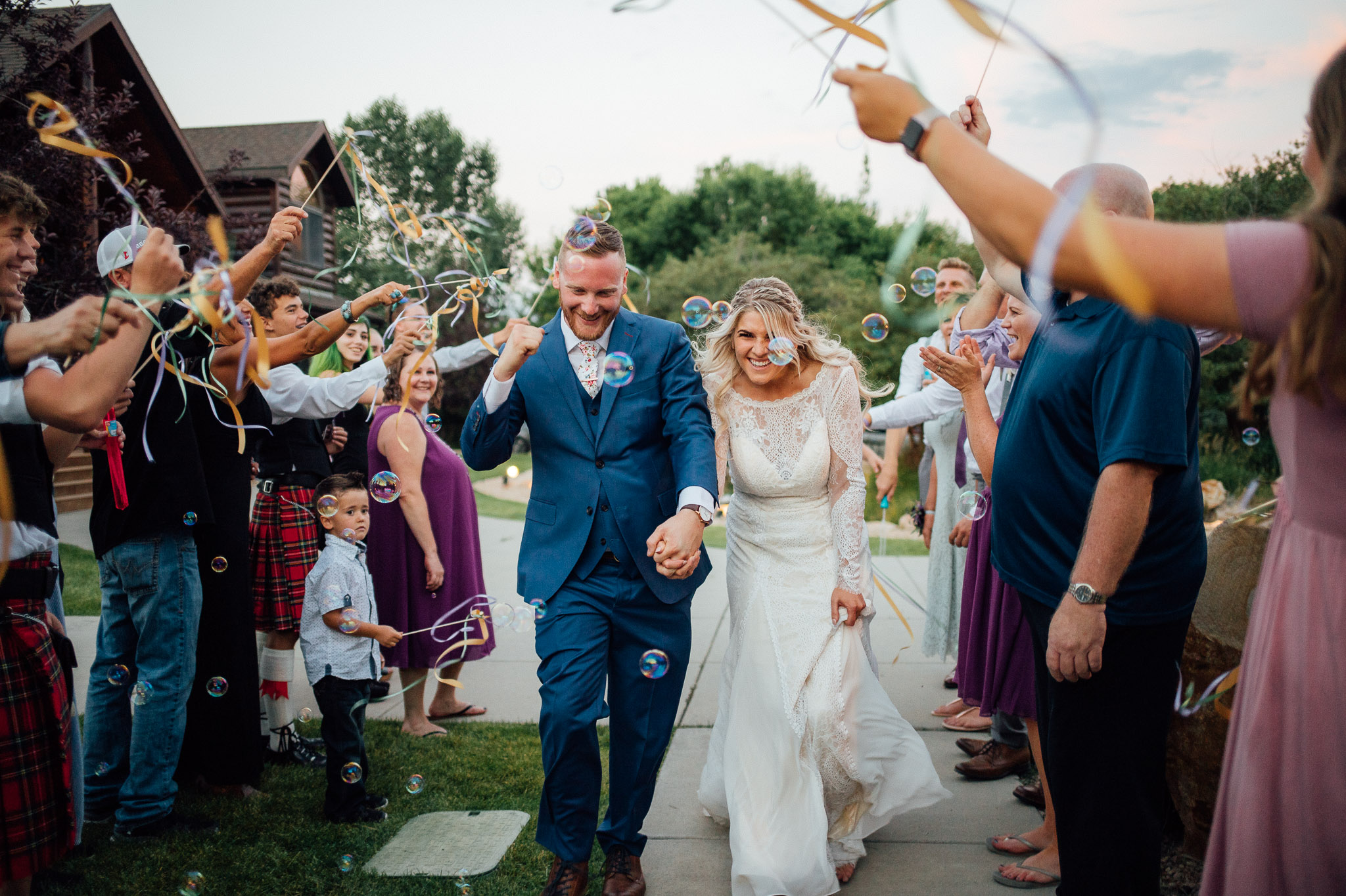 Guests wave ribbons as bride and groom exit wedding reception