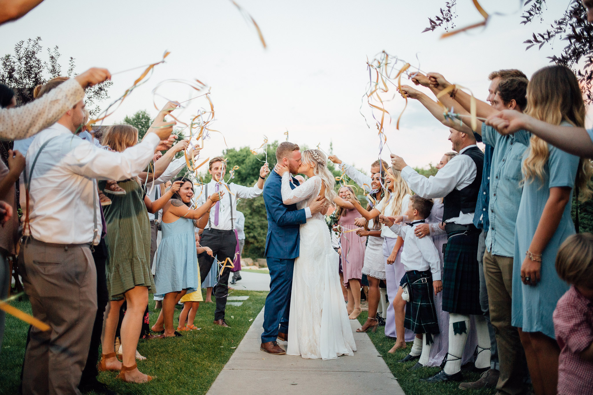 Guests wave ribbons as bride and groom exit wedding reception