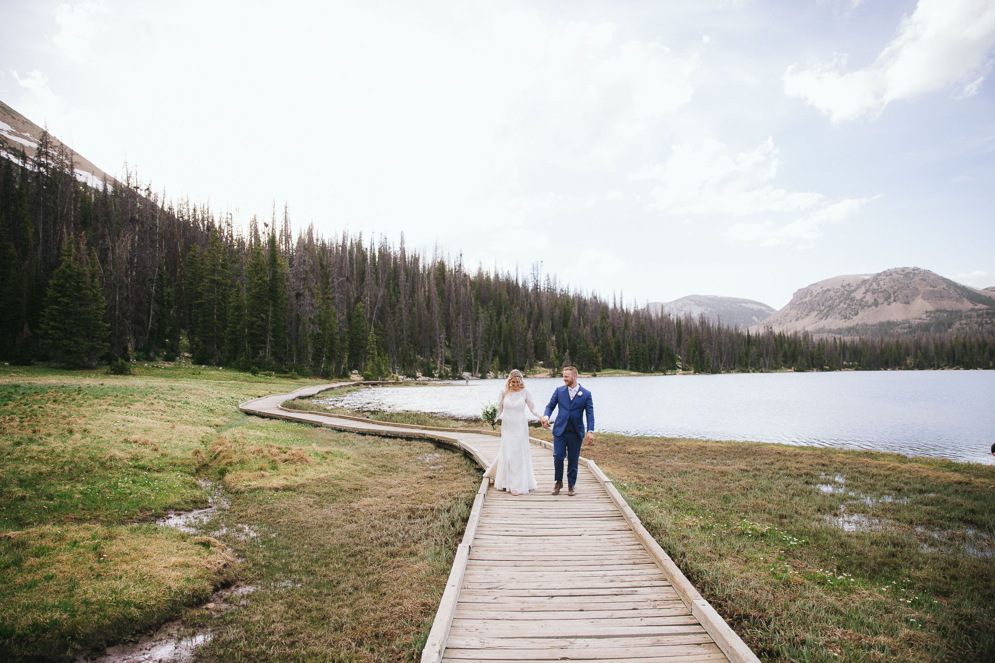 Bride and Groom pose for wedding photos at Mirror Lake in the Utah Mountains