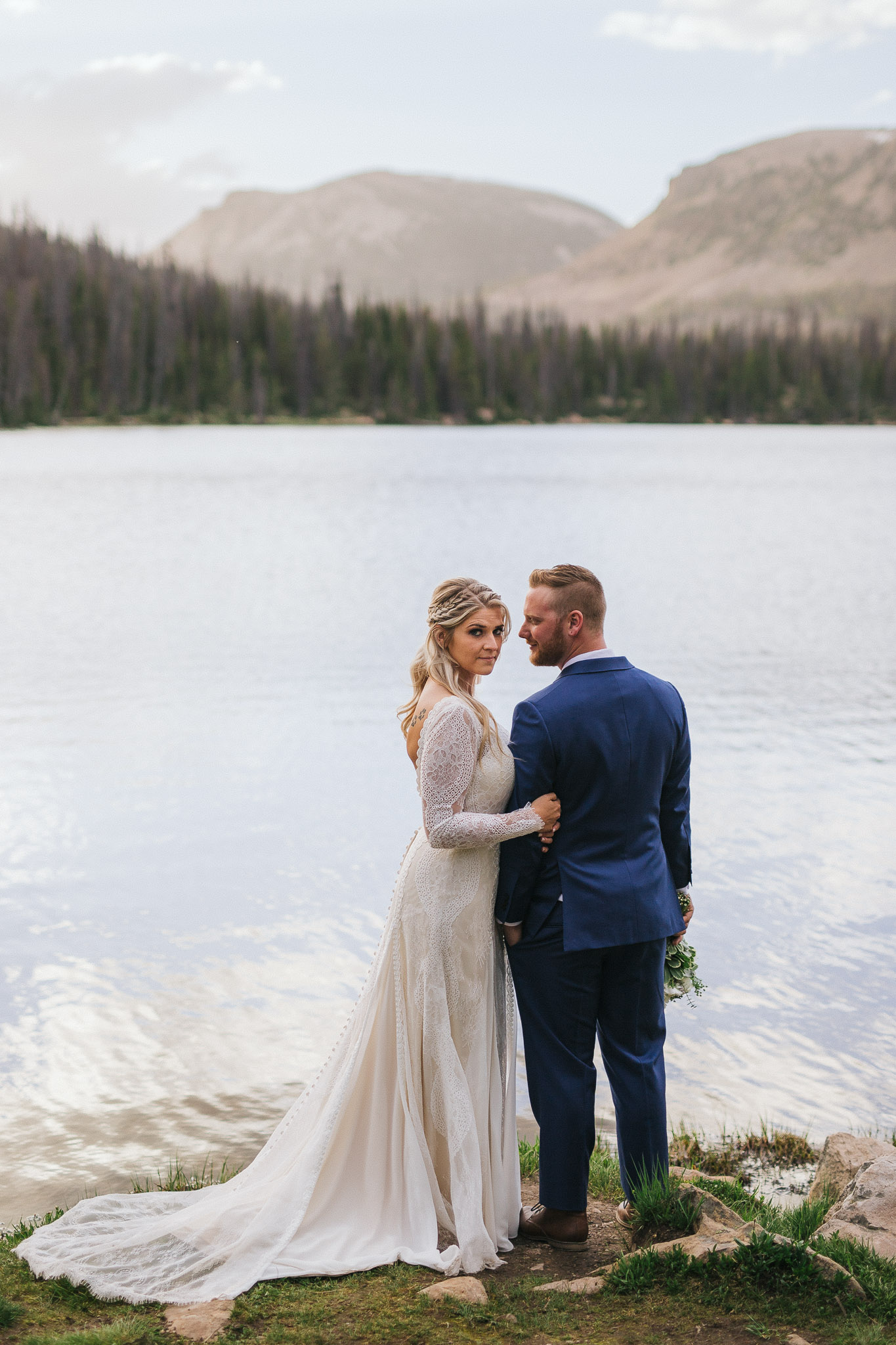 Bride and Groom pose for wedding photos at Mirror Lake in the Utah Mountains
