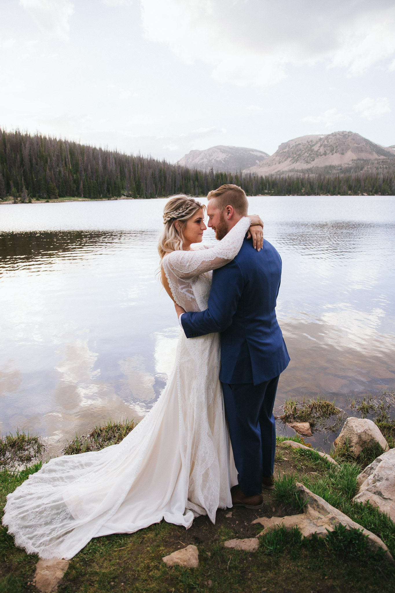 Bride and Groom pose for wedding photos at Mirror Lake in the Utah Mountains