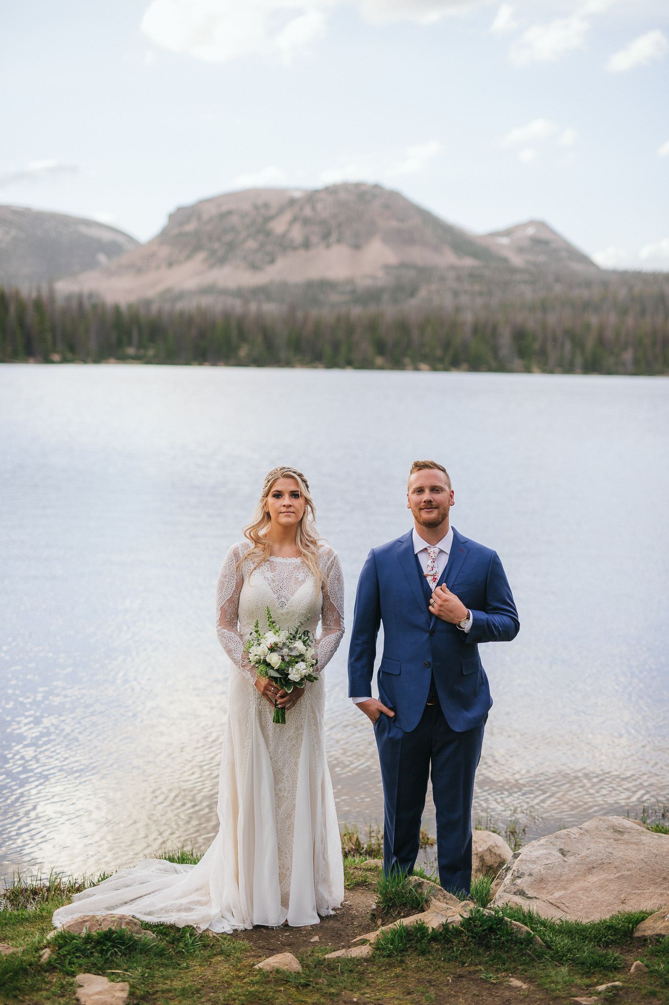 Bride and Groom pose for wedding photos at Mirror Lake in the Utah Mountains