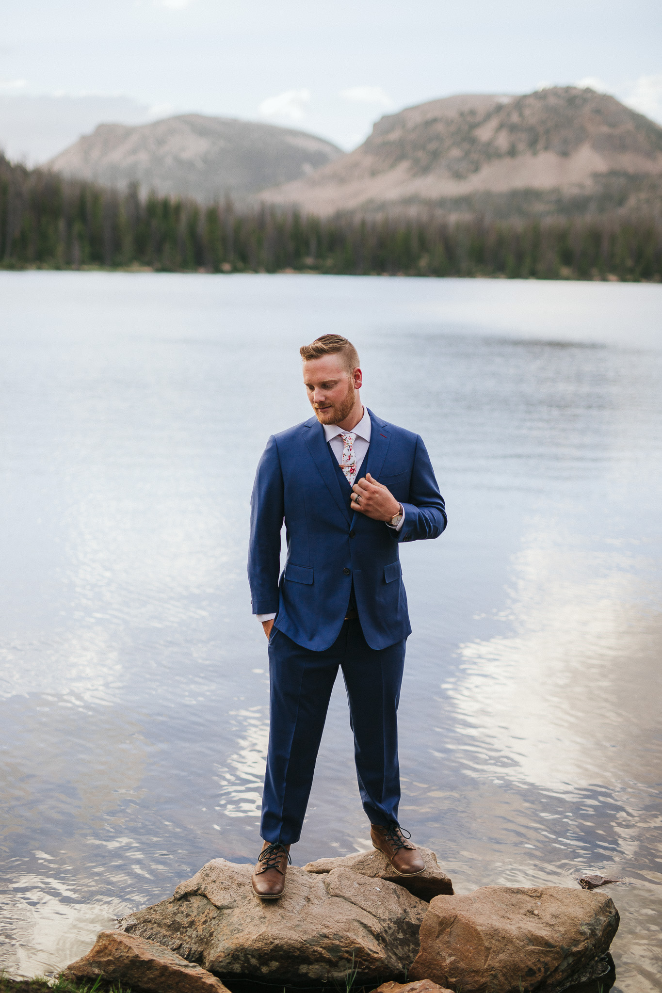 Groom poses for wedding photos at Mirror Lake in the Utah Mountains