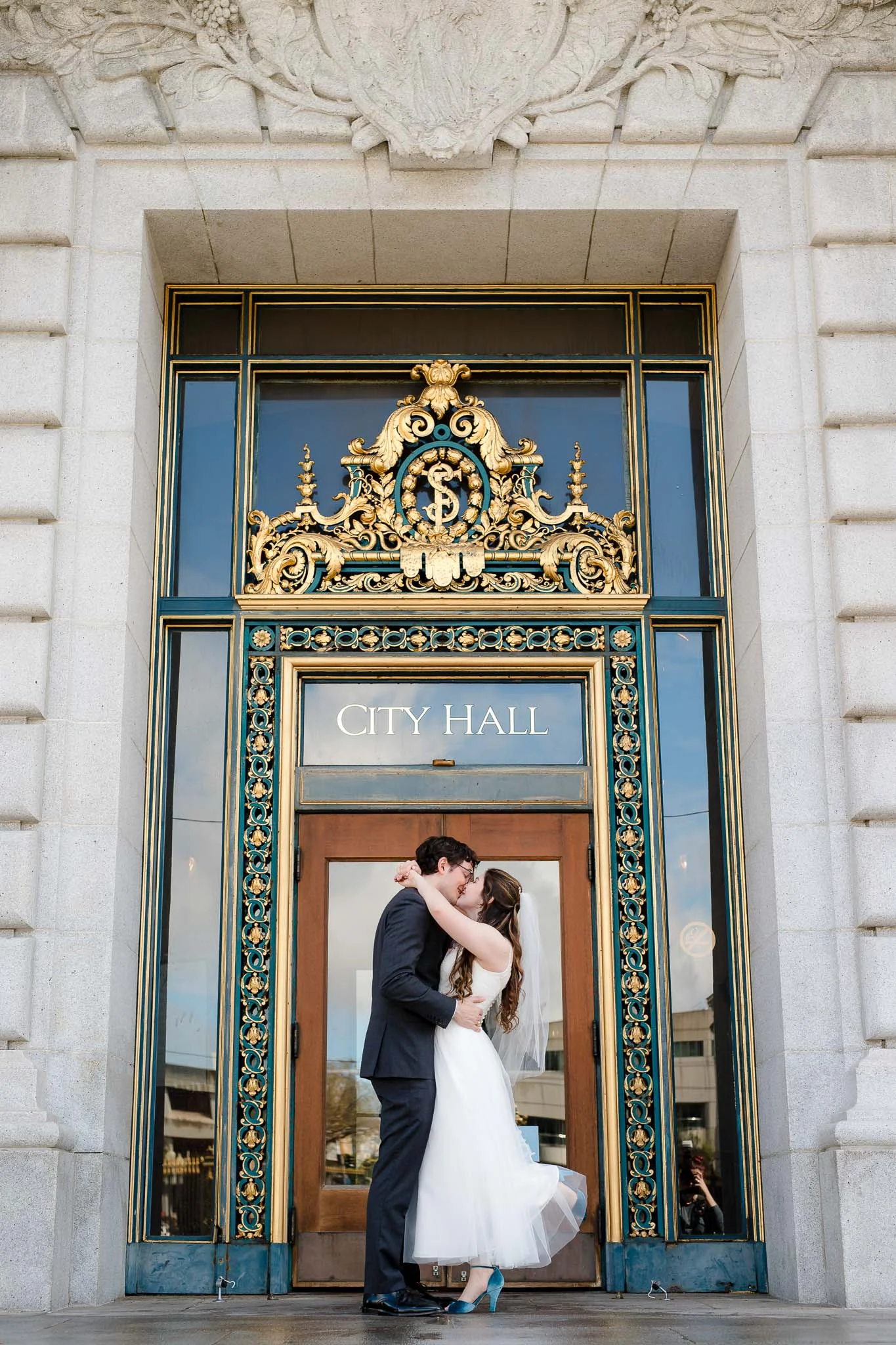 Couple kiss outside San Francisco City Hall doors after their elopement ceremony