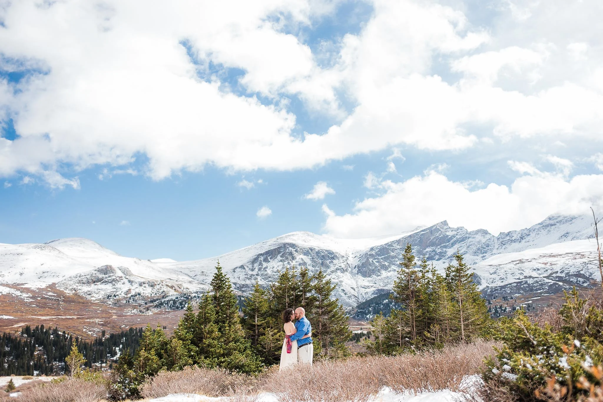 Husband and wife kiss in front of mountain vista including Mt. Beirstadt during their Guanella Pass vow renewal in Colorado