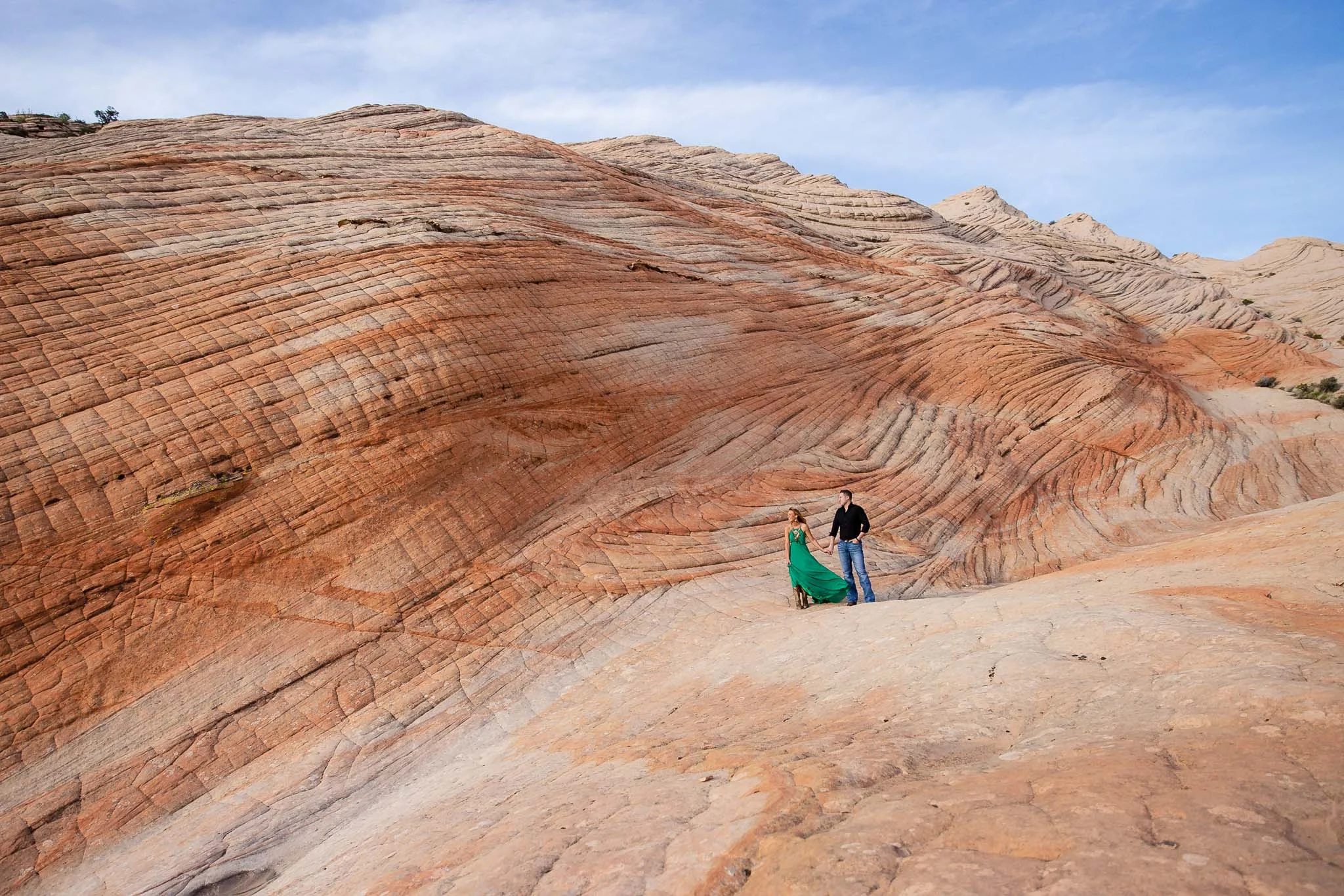 Couple hold hands in the epic swirling red rocks near St. George Utah for their adventure session