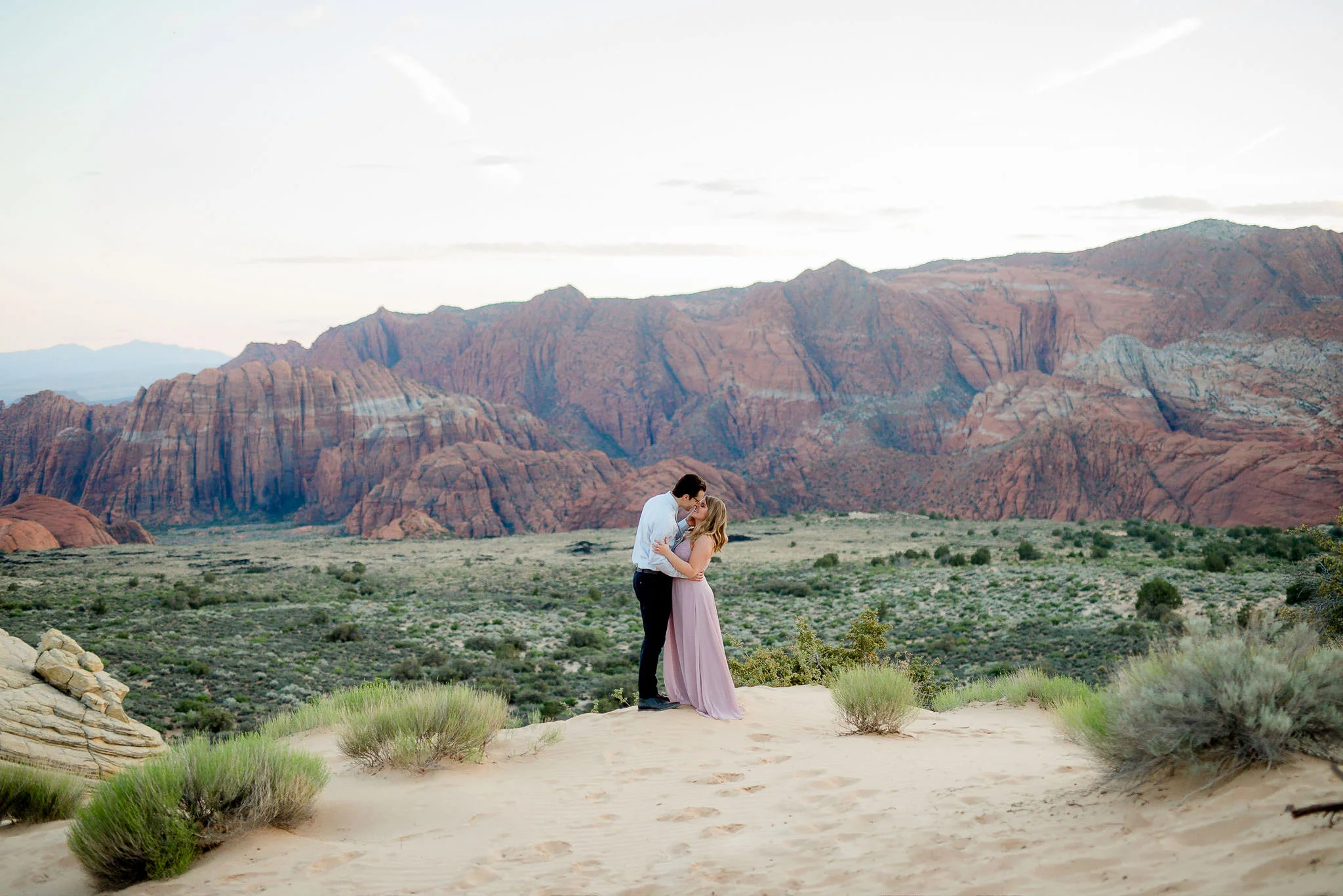 Couple embrace overlooking Snow Canyon State Park for their Utah Adventure Engagement Session