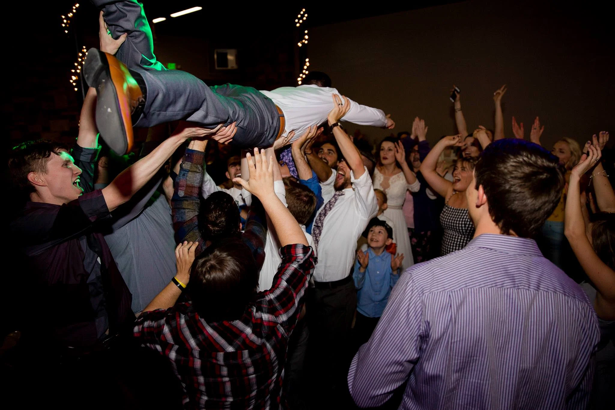 Groom crowd surfing Utah wedding reception