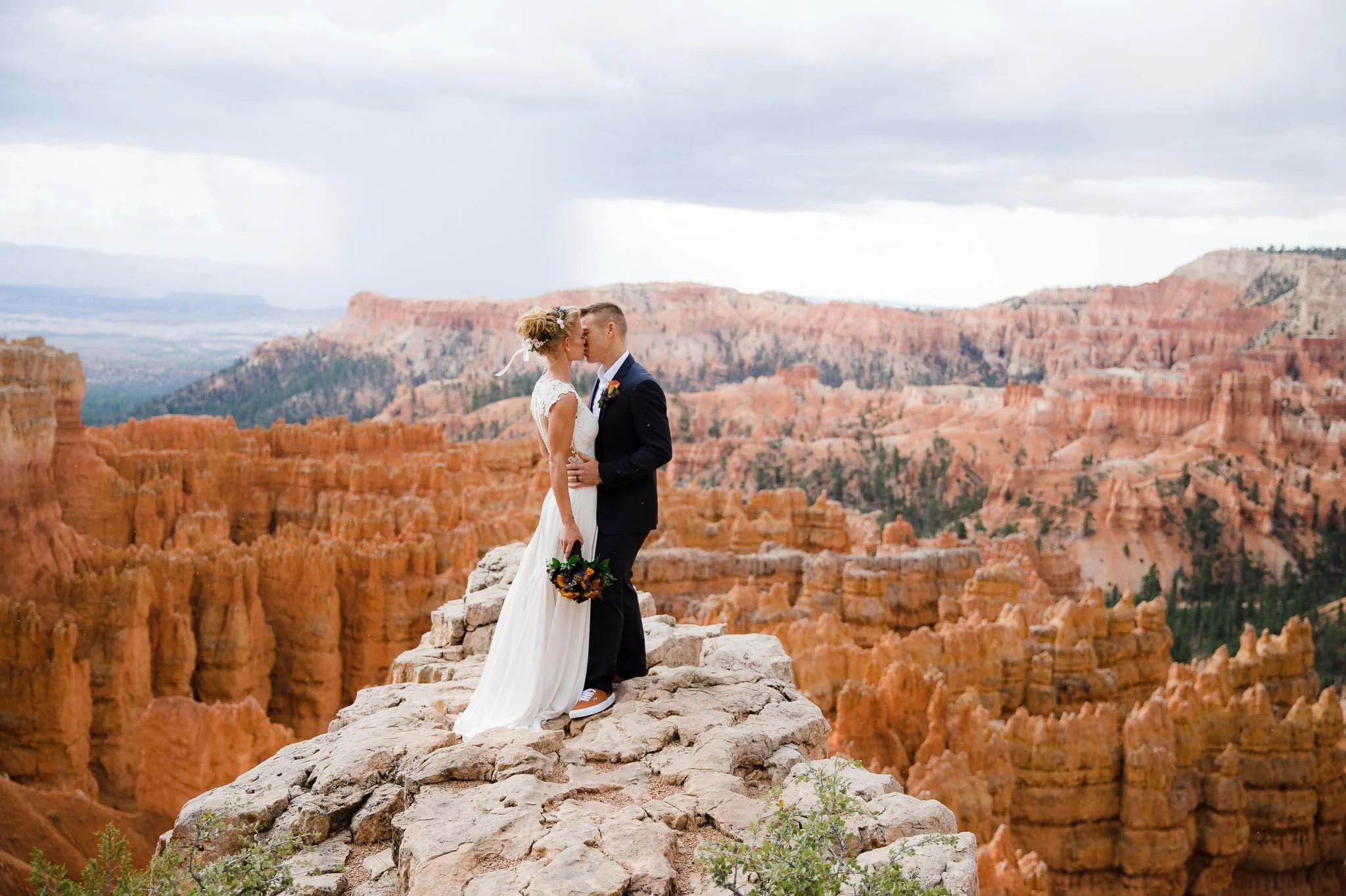 Bride and groom kiss overlook hoodoos in Bryce Canyon National Park Utah