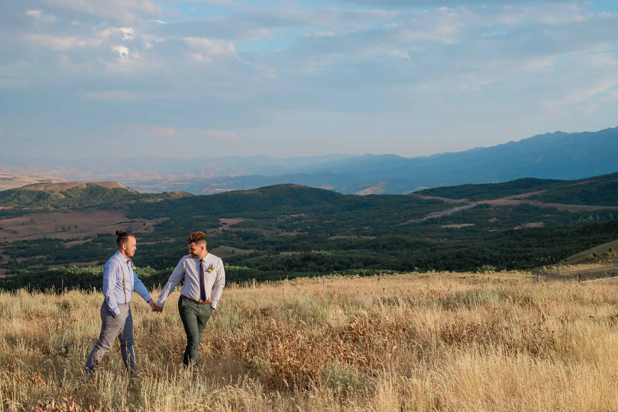 Two grooms walk in front of Utah mountain skyline wedding photographer