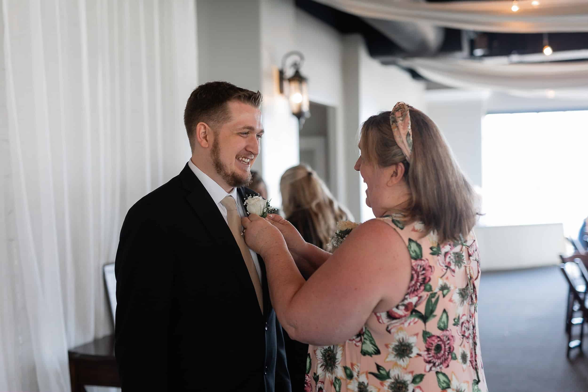 Mother of the groom pins boutonniere on the groom before his wedding ceremony Utah Wedding Photographer