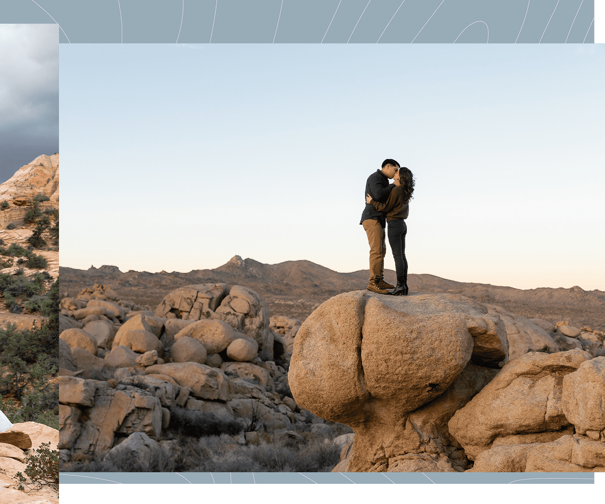 Couple hug while standing on a rock near Joshua Tree National Park California for their engagement photoshoot