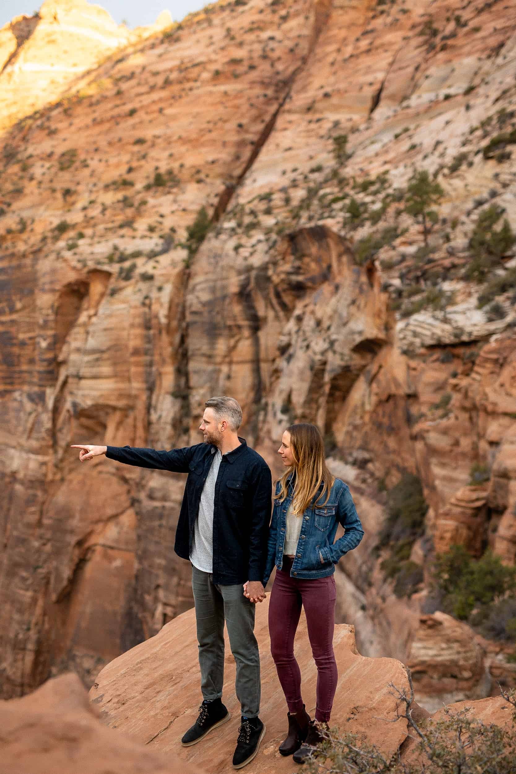 Couple stands admiring the view in Zion National Park during their adventure engagement photos in Utah