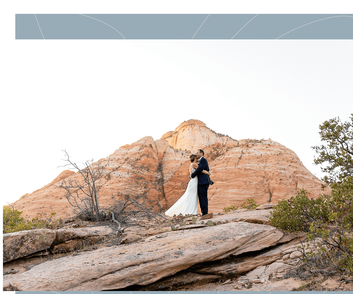 Couple hug with a Zion National Park peak behind them during their wedding portrait photoshoot