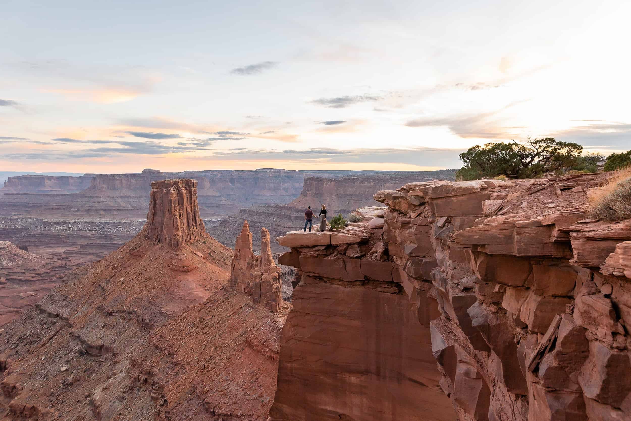 Epic landscape image of a couple standing in front of canyons during their adventure anniversary session in Moab Utah