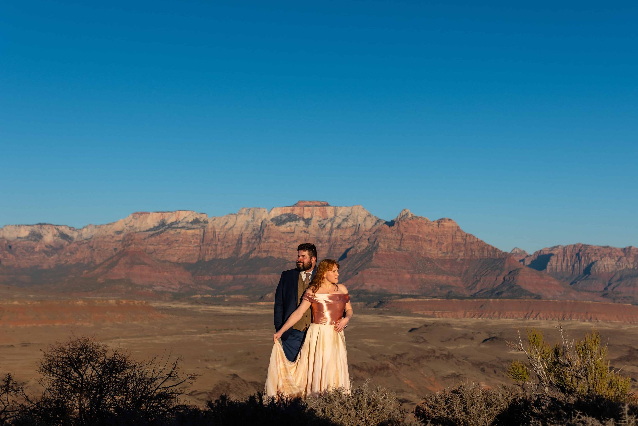 Bride and groom pose for portraits at sunset in front of Zion National Park during their Zion Helicopter Butte Landing experience