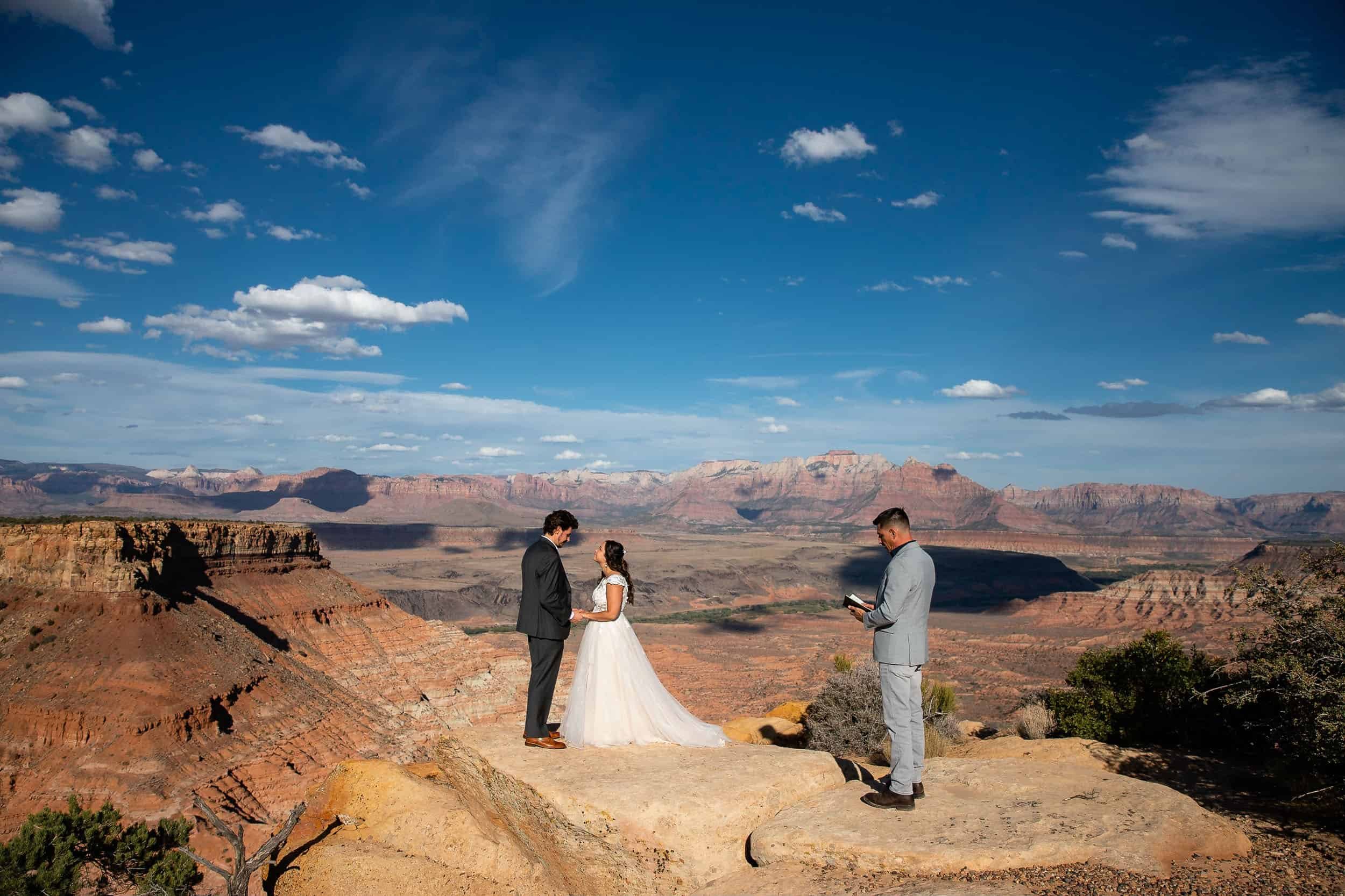 Couple stand in front of an epic view of Zion National Park with their officiant off to the side for their National Park Elopement