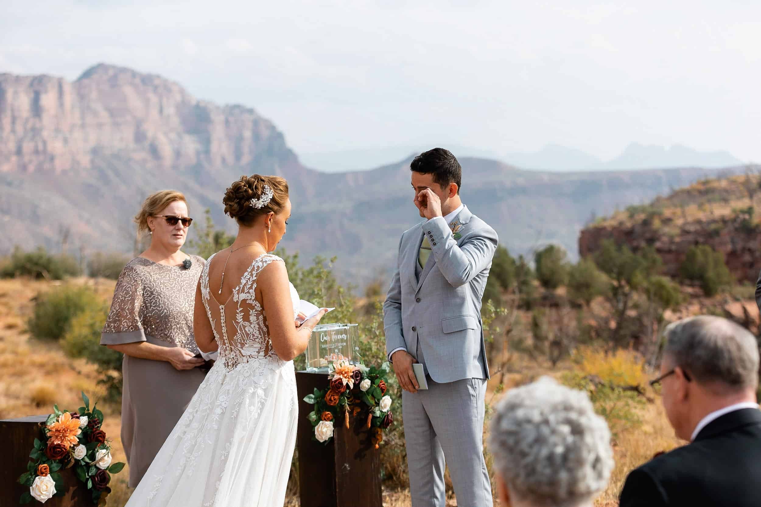 Groom wipes a tear from his eye while bride shares her vows during their Zion National Park elopement