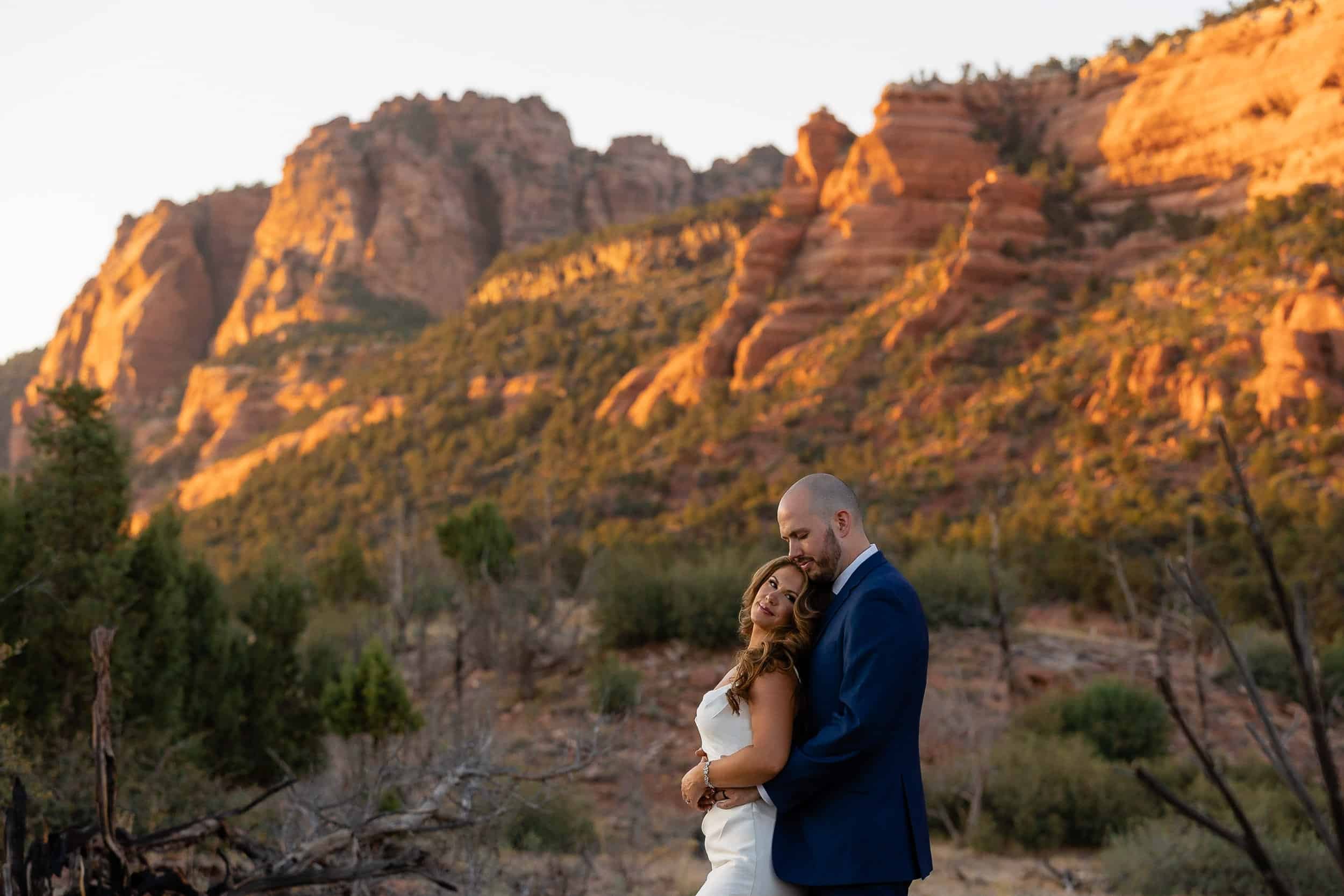 Bride leans back on her groom while he holds her during their sunset portraits in Zion National Park