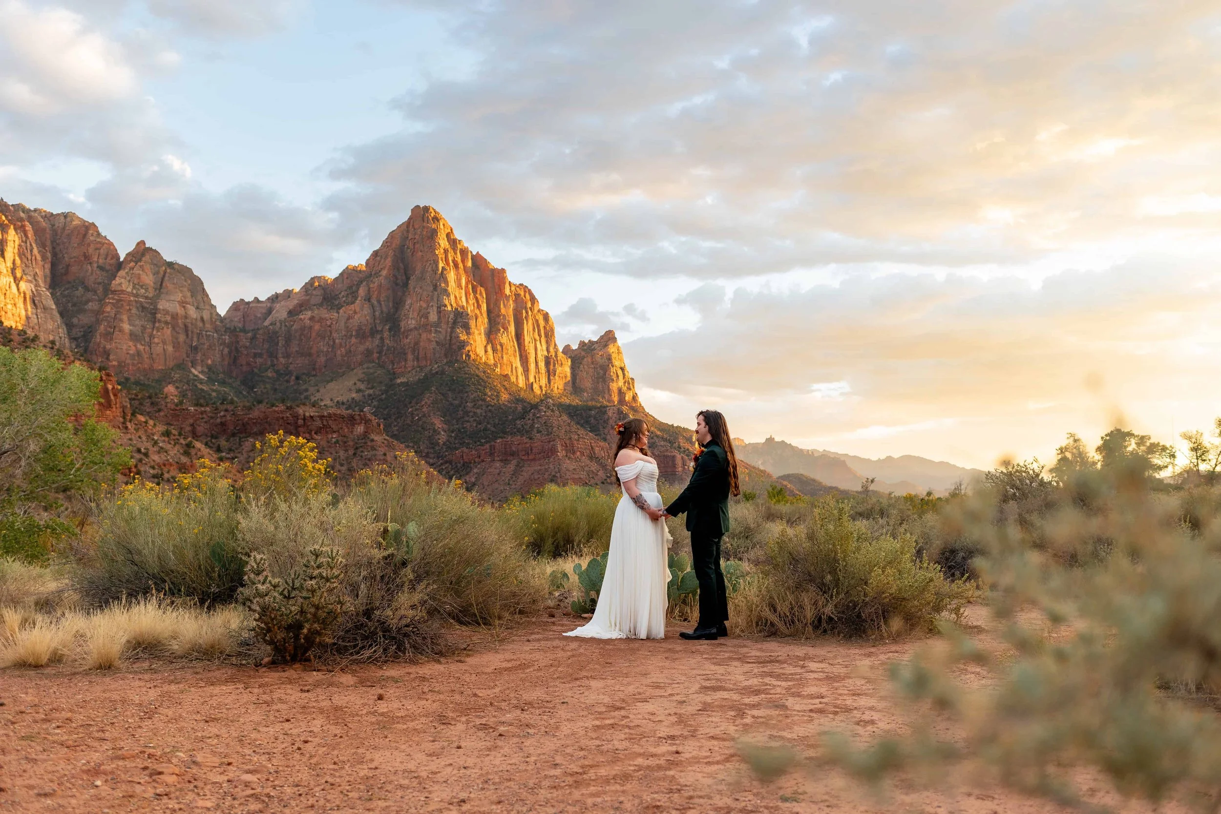 Bride and groom hold hands while posing in zion at sunset for portraits