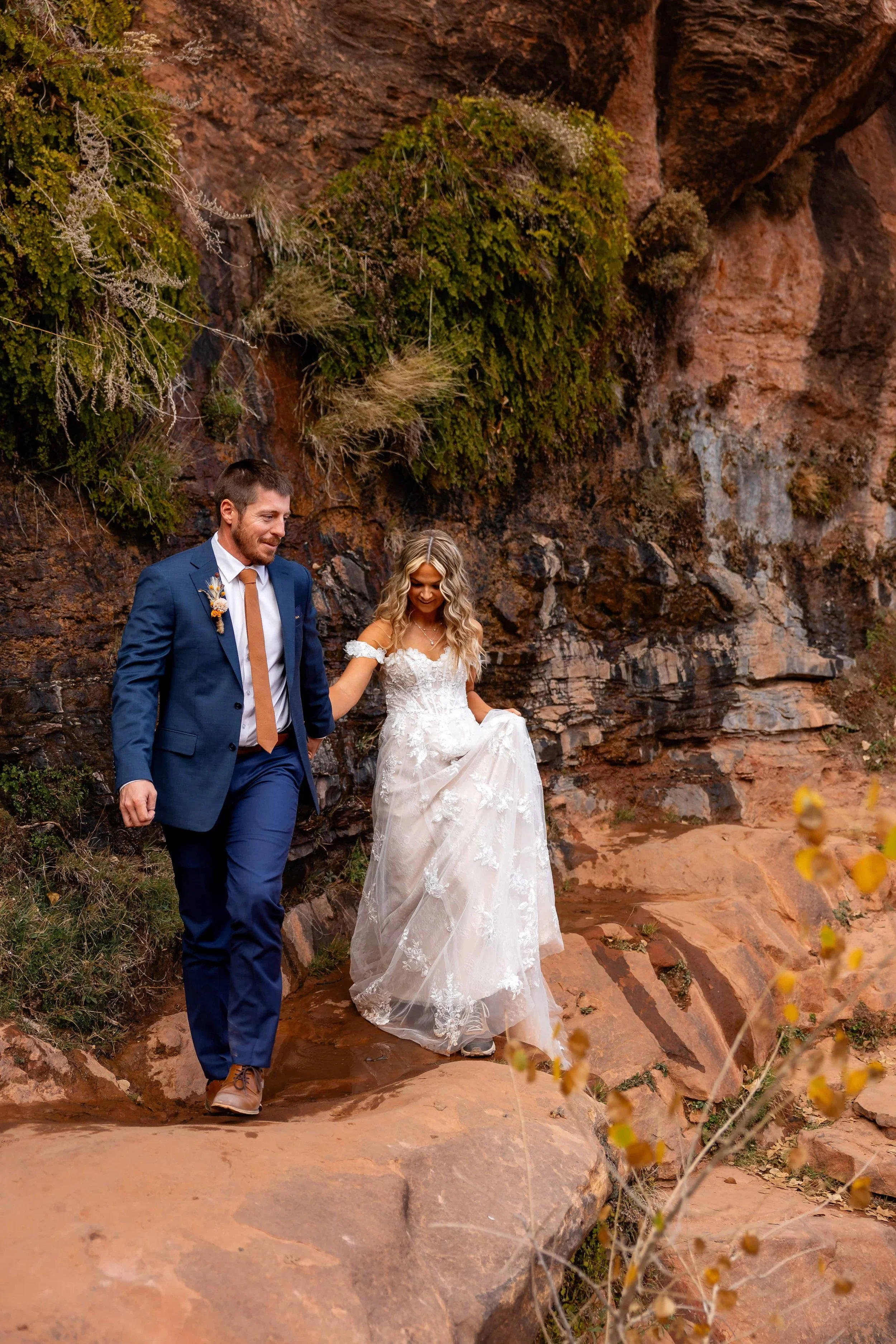 bride and groom walk together on canyon overlook hike