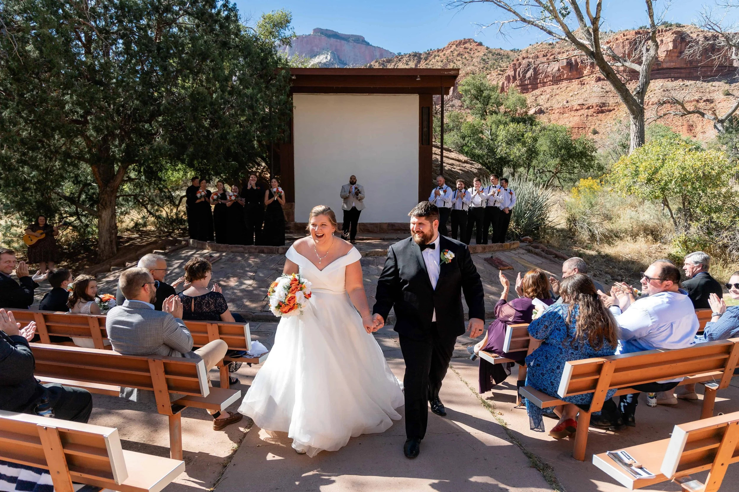 Bride and groom exit amphitheater ceremony holding hands