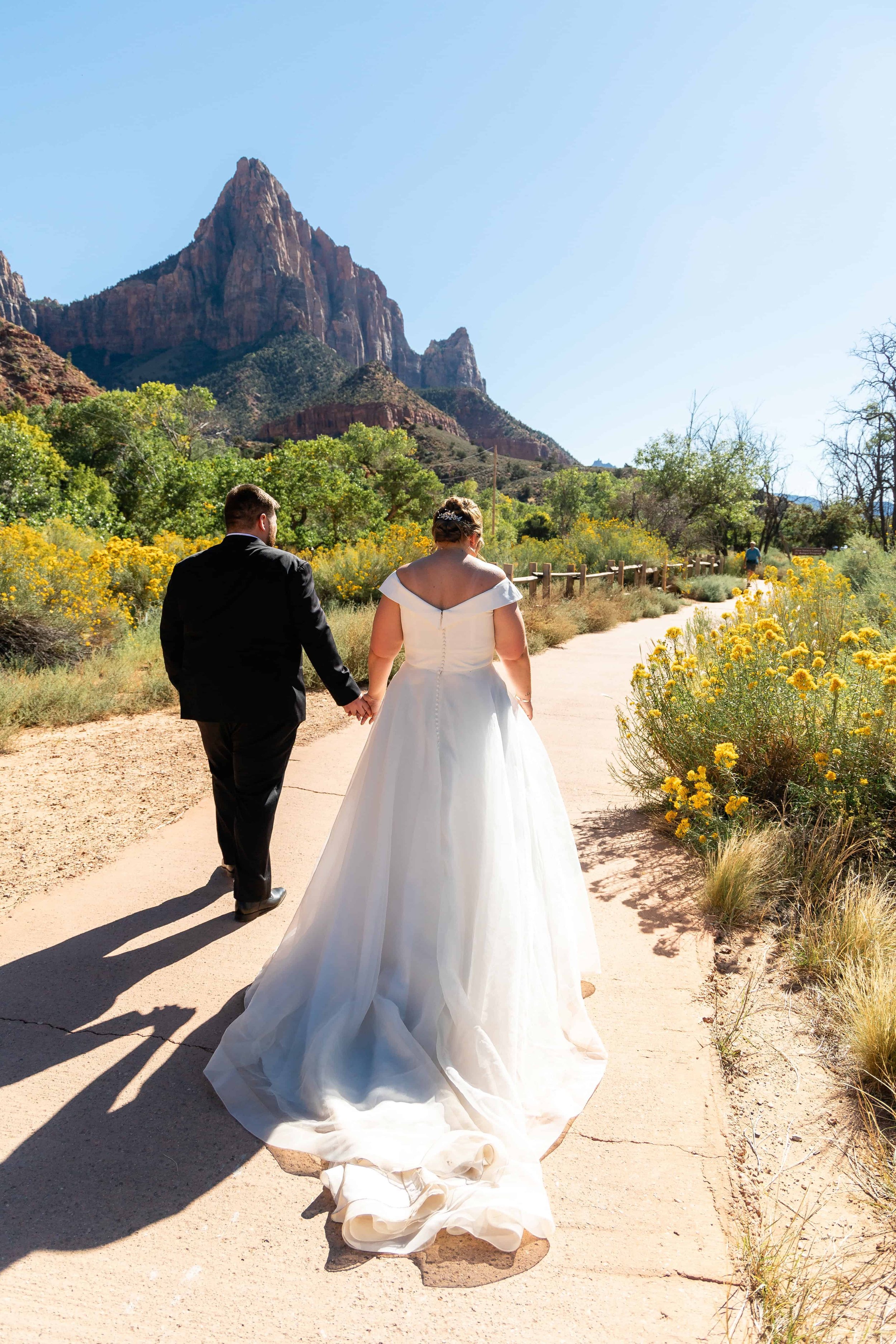 Bride and groom walk together on Pa'rus trail after wedding at south campground amphitheater