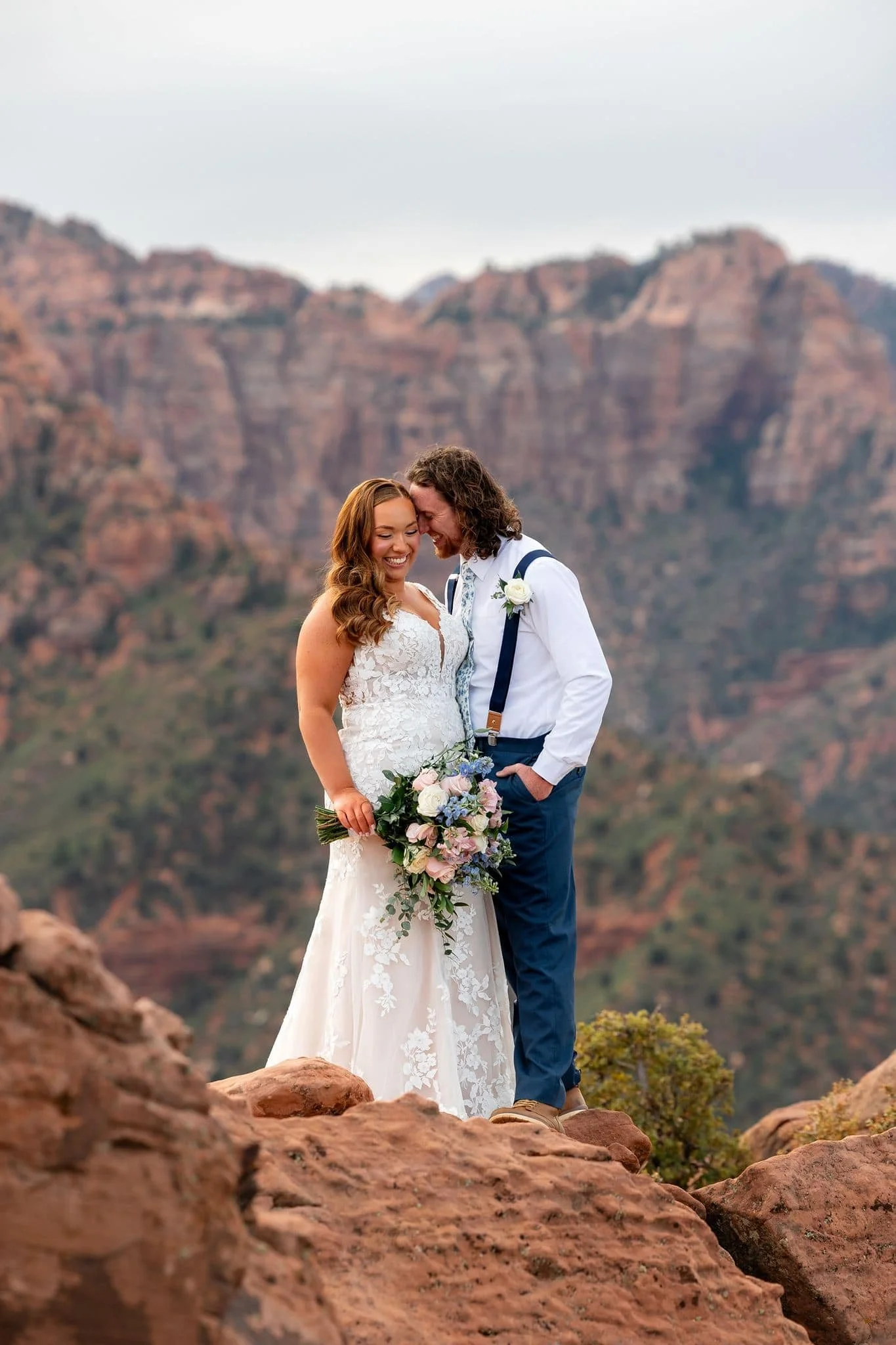 Wedding couple presses heads together while posing for photos at Timber Creek Overlook