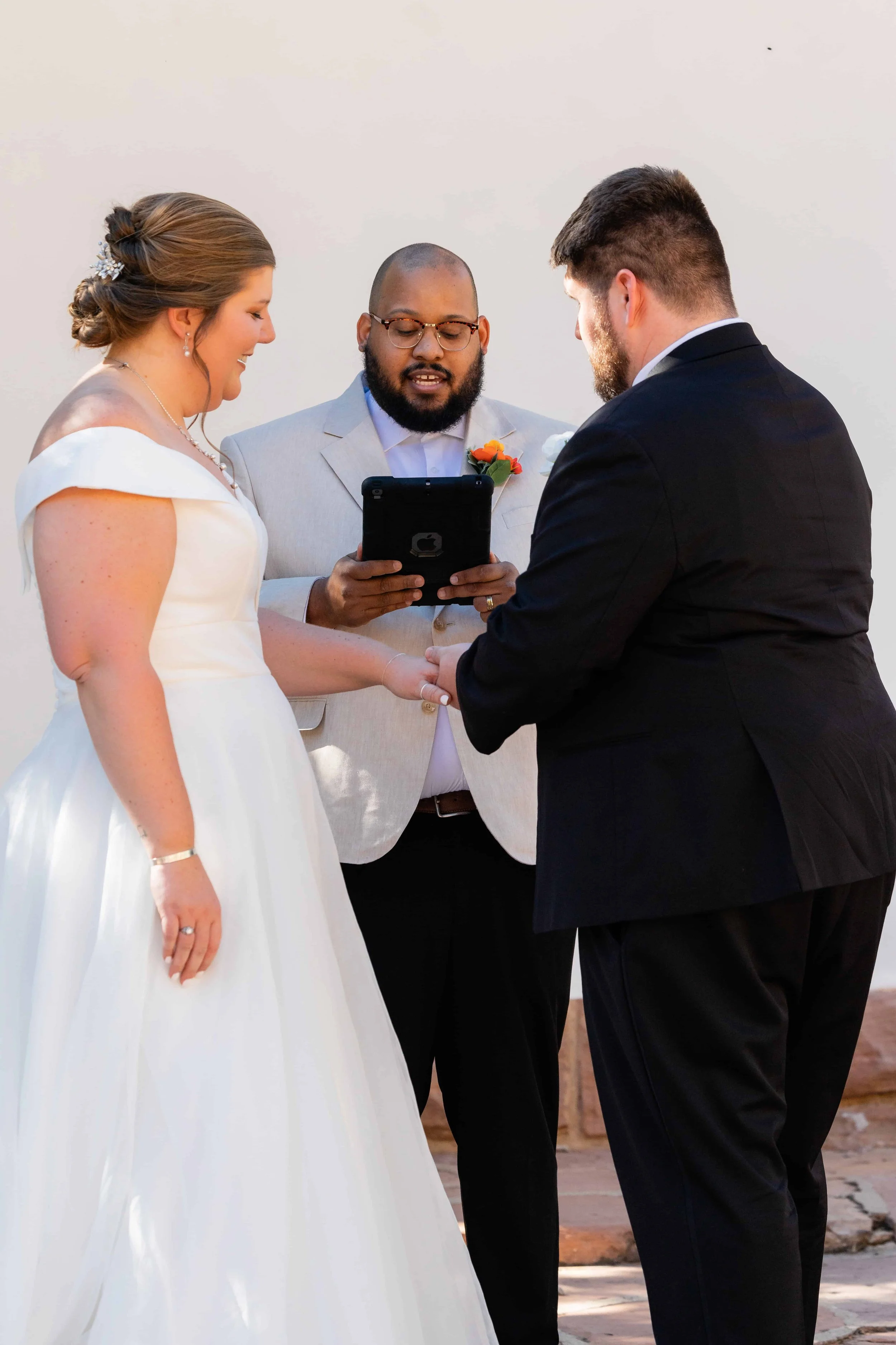 Groom puts ring on bride's finger during south campground amphitheater wedding ceremony