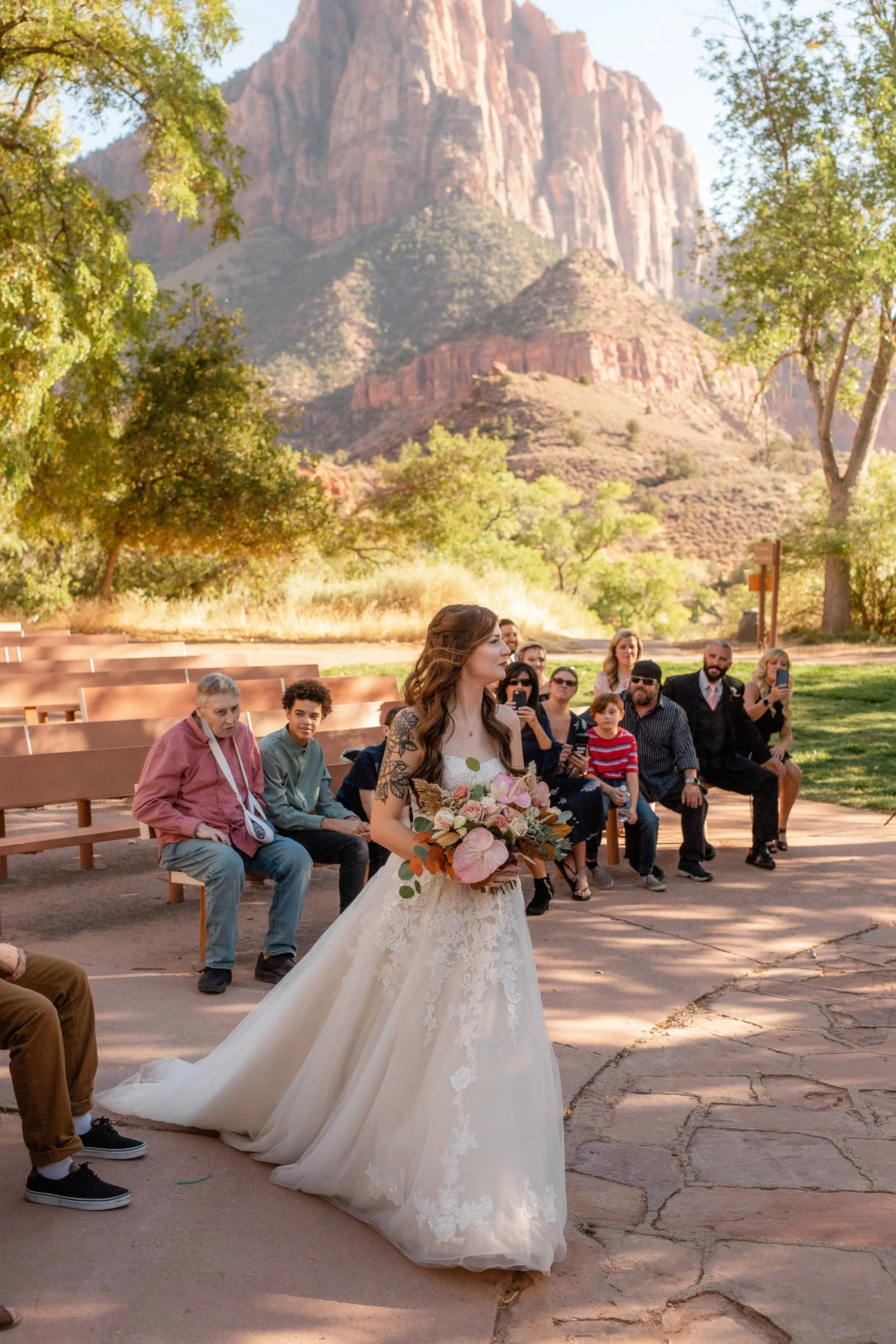 Bride walks into ceremony at south campground amphitheater holding bouquet