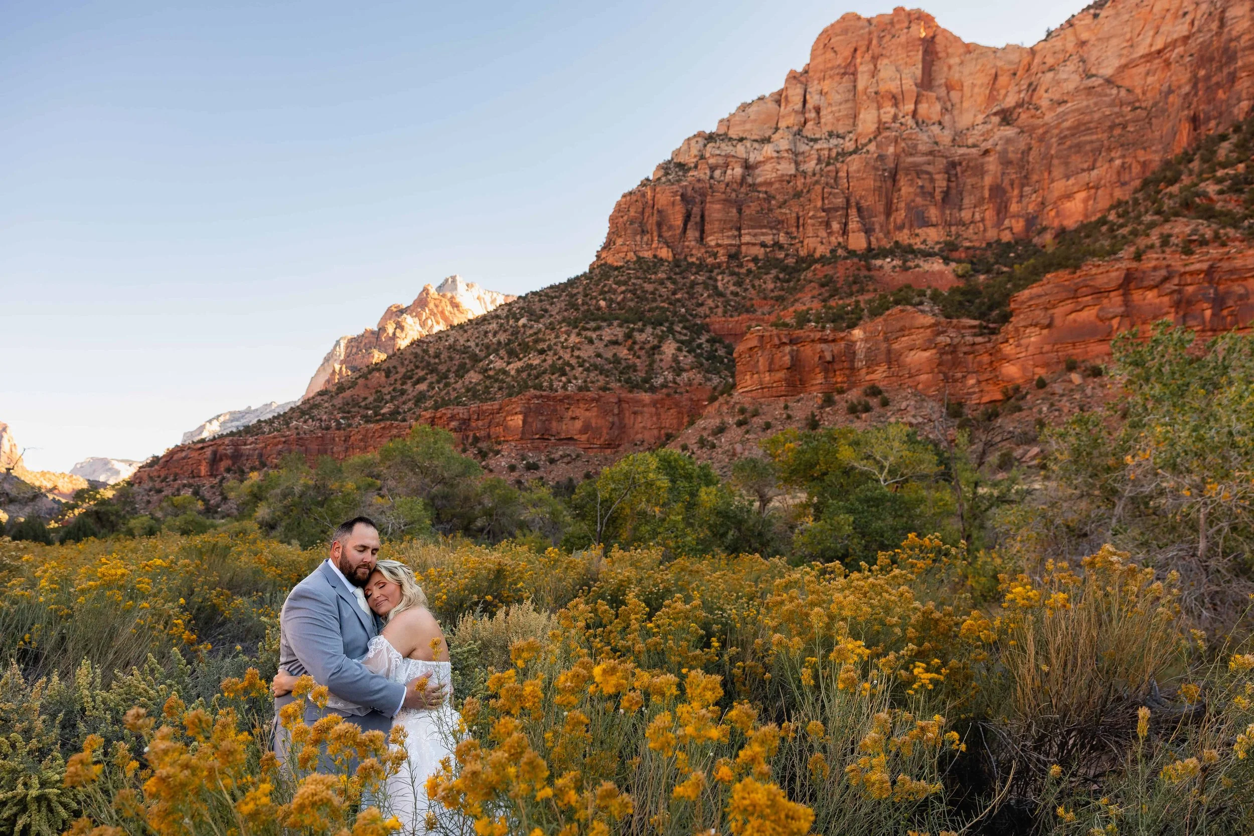 bride and groom hug during portrait session among golden flowers in zion
