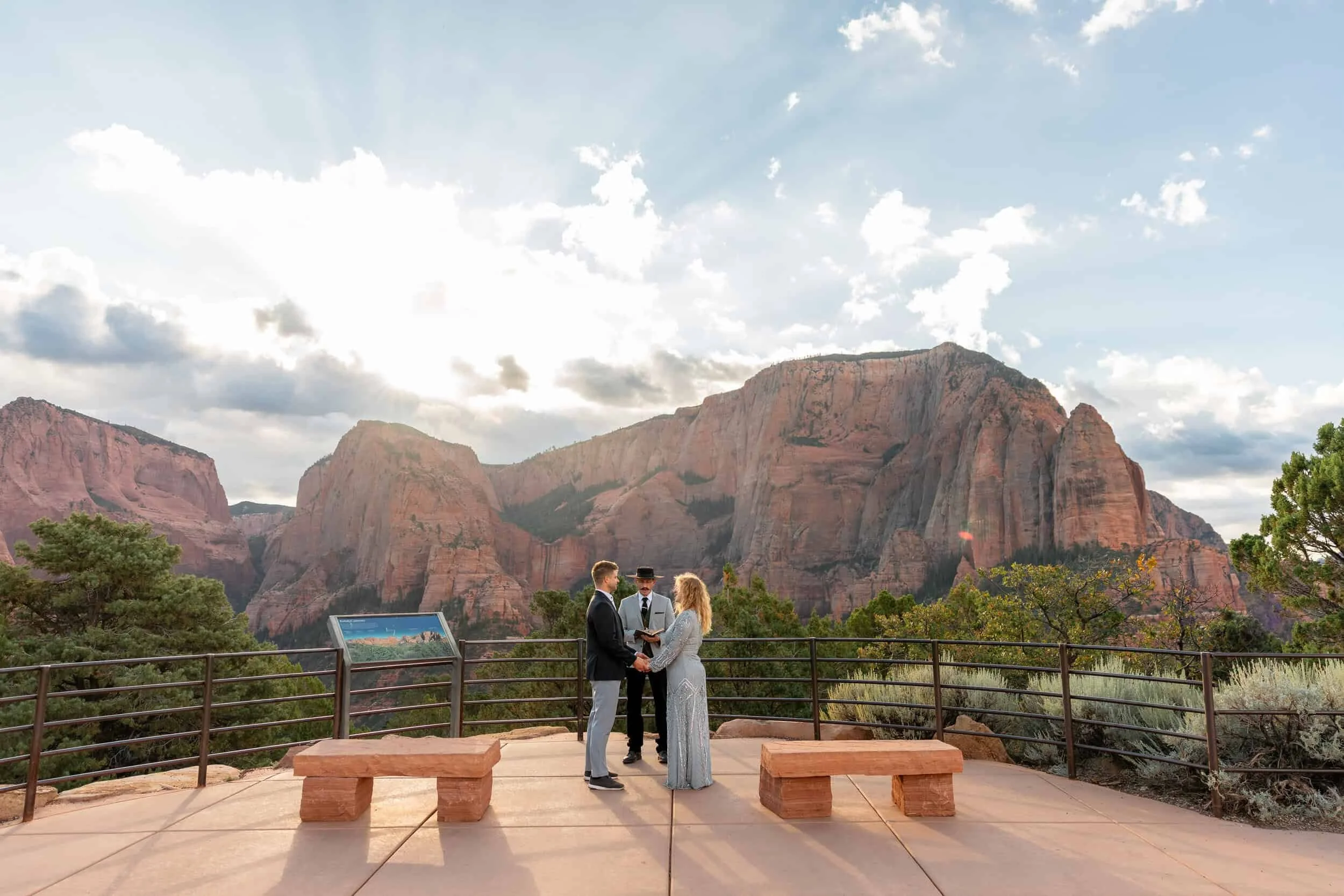 Couple stands holding hands in front of an officiant at the Kolob Viewpoint wedding location in Zion National Park during their elopement ceremony