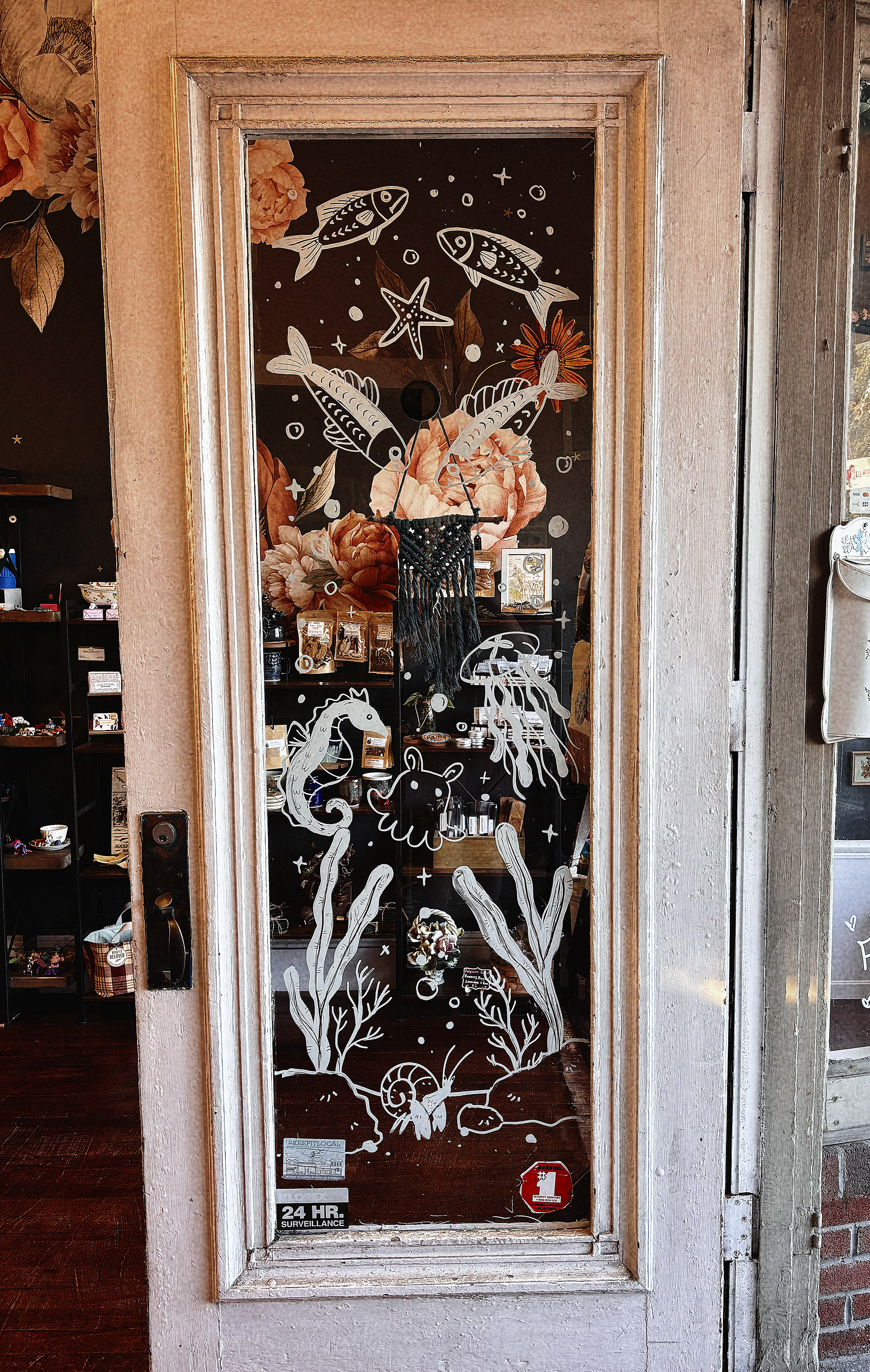 Glass door with hand-painted white fish, starfish, seahorse, seashells, and marine plants.