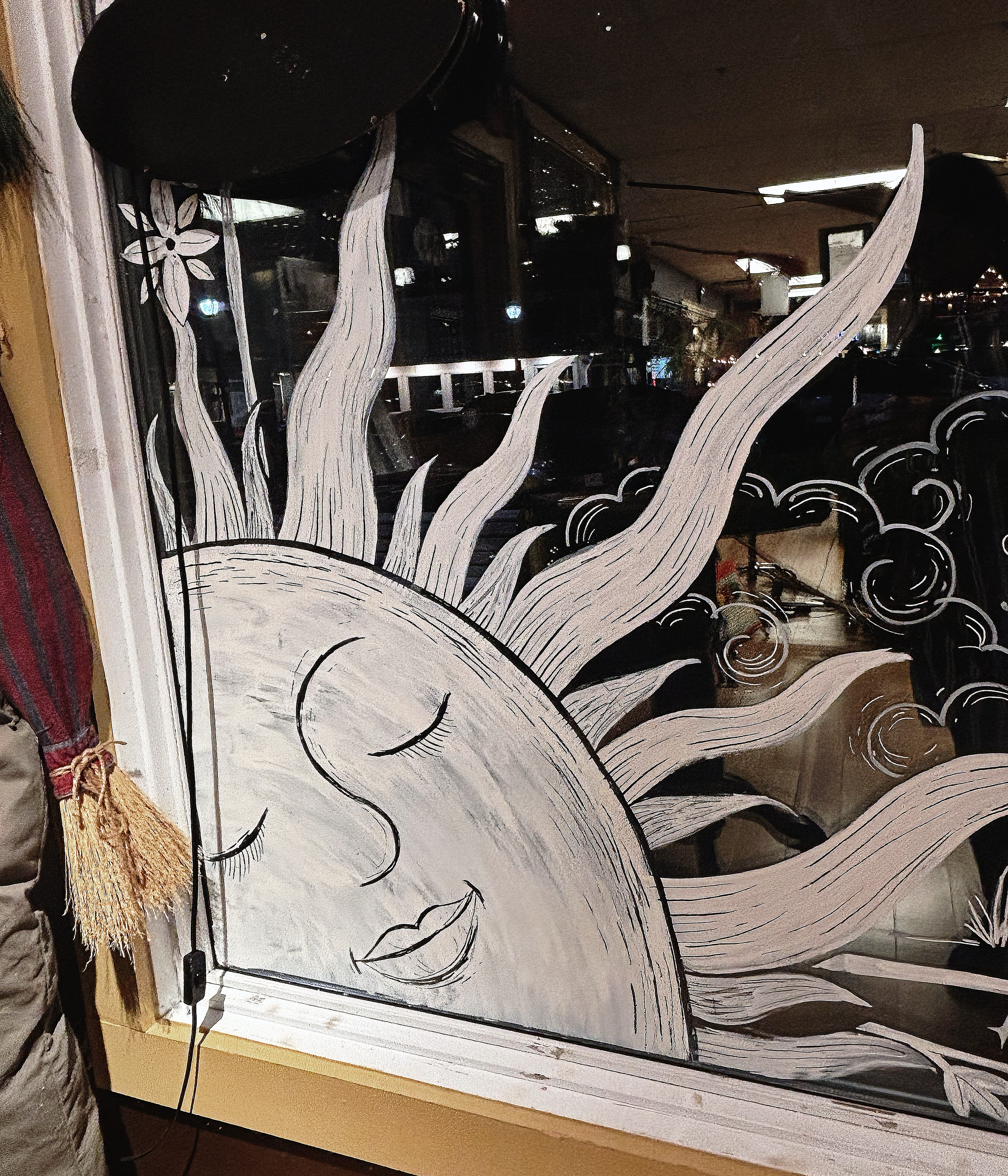 Glass window with white and black artistic floral design featuring a large blooming flower and swirling patterns.