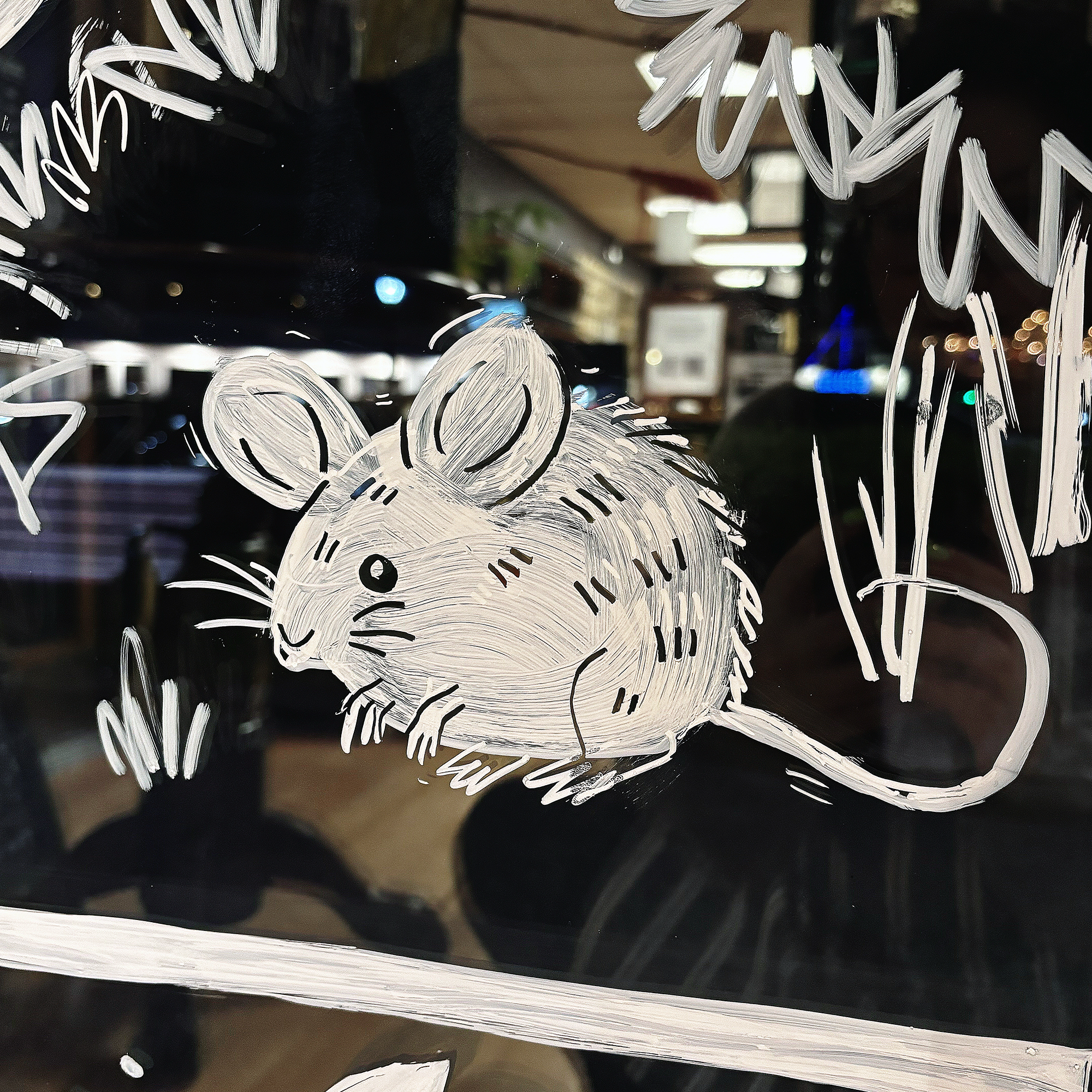 A white hand-painted mouse on a glass window.