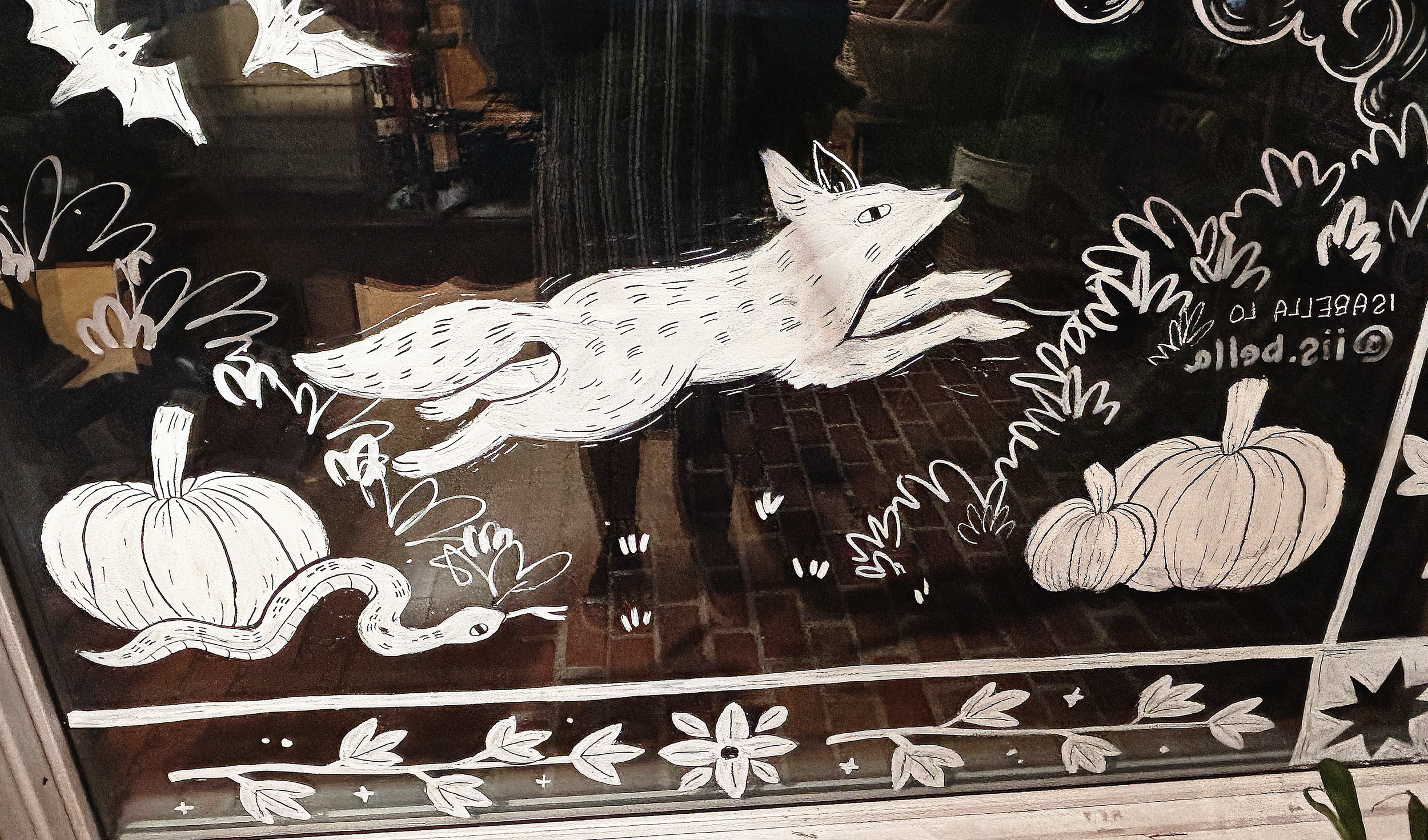 Hand-painted snake, pumpkin, and fox with Halloween-themed elements on glass window.